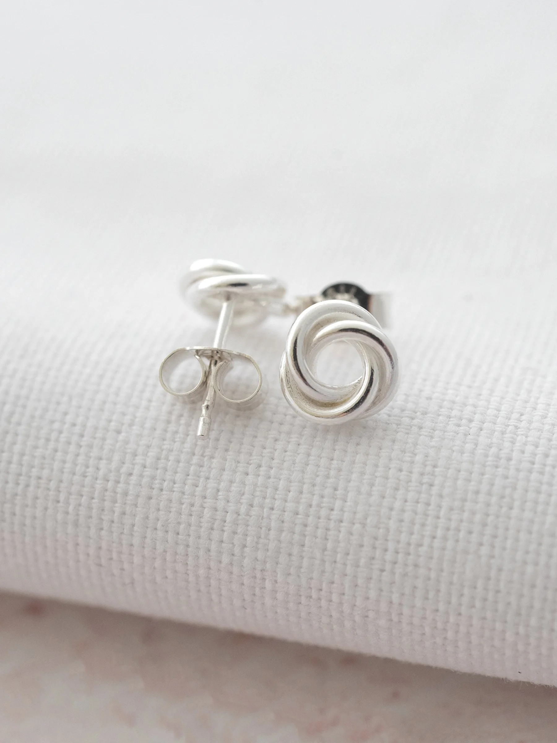 A front and back view of a pair of 30th stud earrings displayed over white material.