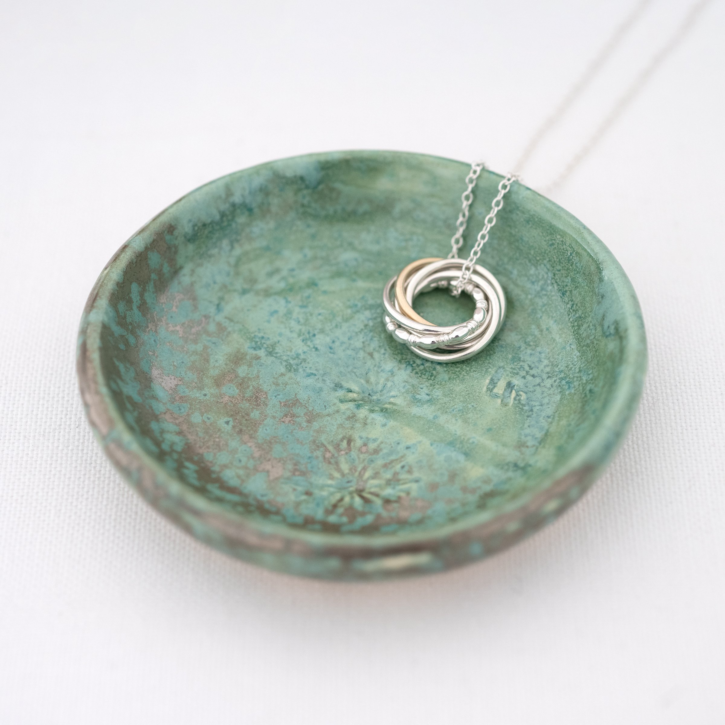 A mottled green jewellery dish displaying a 40th birthday necklace.