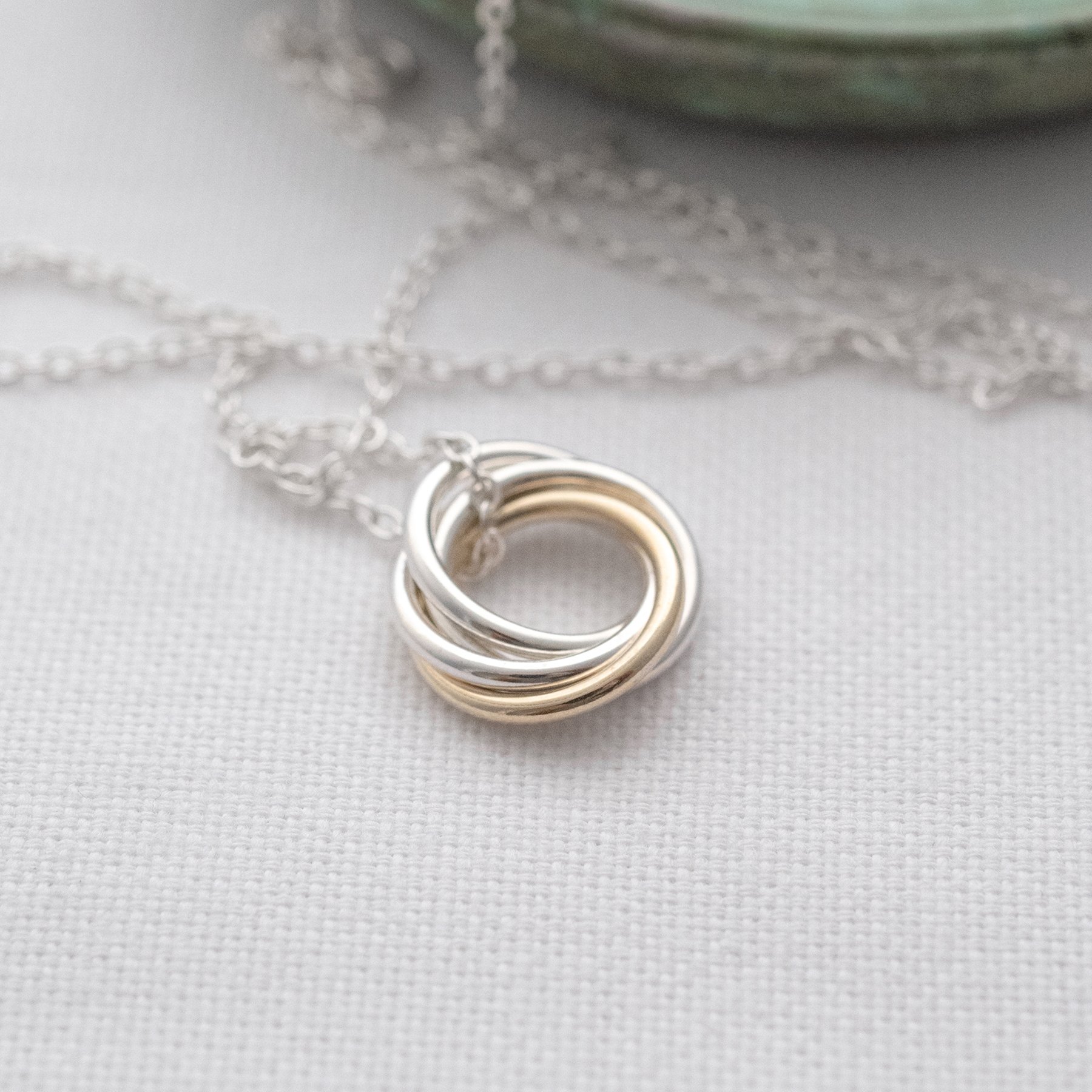 A gold and silver 40th birthday necklace displayed on white material.