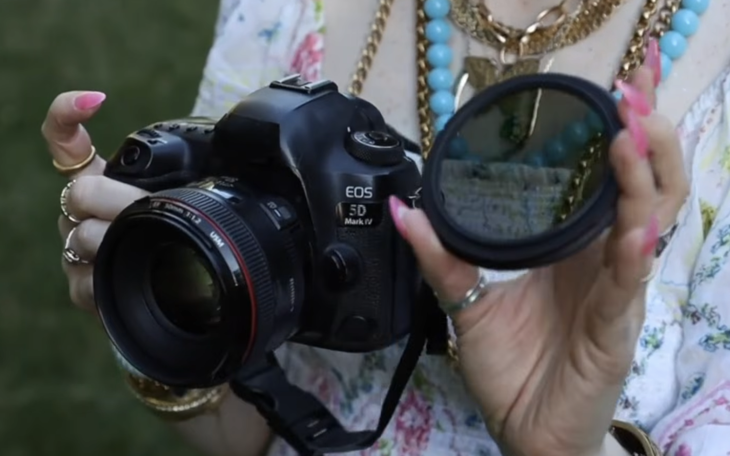 A variable ND filter placed next to a DSLR camera with a prime lens before being attached for shooting in direct sunlight.