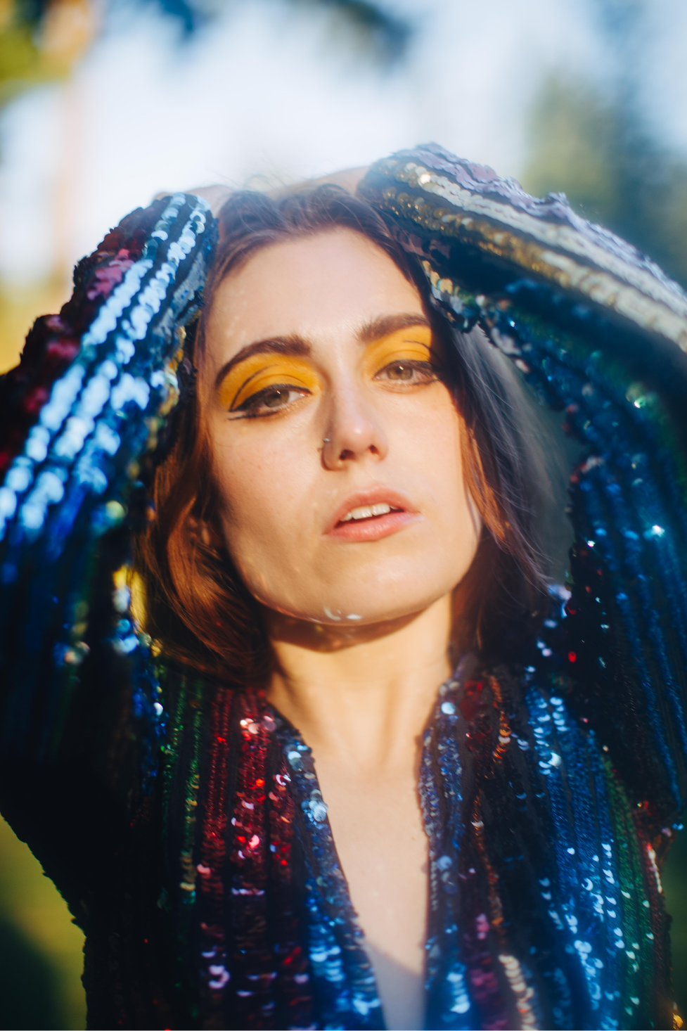A model in a shimmering sequin jumpsuit with a dreamy haze effect created by applying lip balm to a camera lens filter in direct sun.