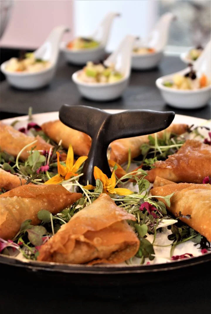 Prato em cerâmica, com cauda escura no centro, feito à mão com salgados e verduras