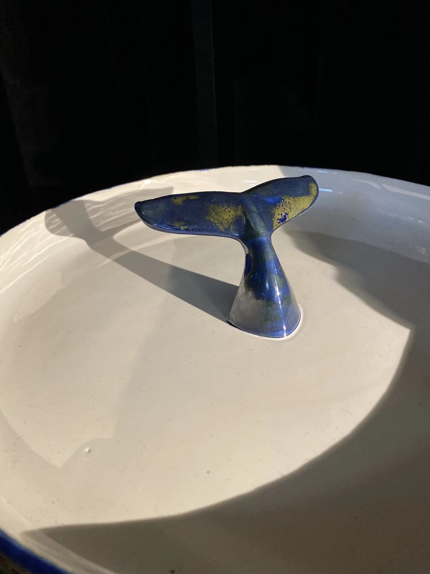 Prato em cerâmica, com cauda escura no centro, feito à mão na cor azul mar e branco no interior