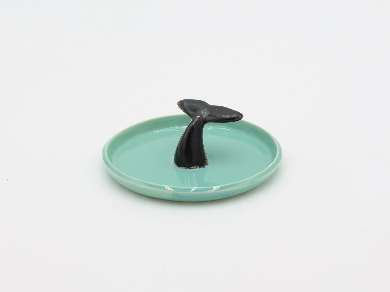 Prato em cerâmica, com cauda escura no centro, feito à mão na cor turquesa