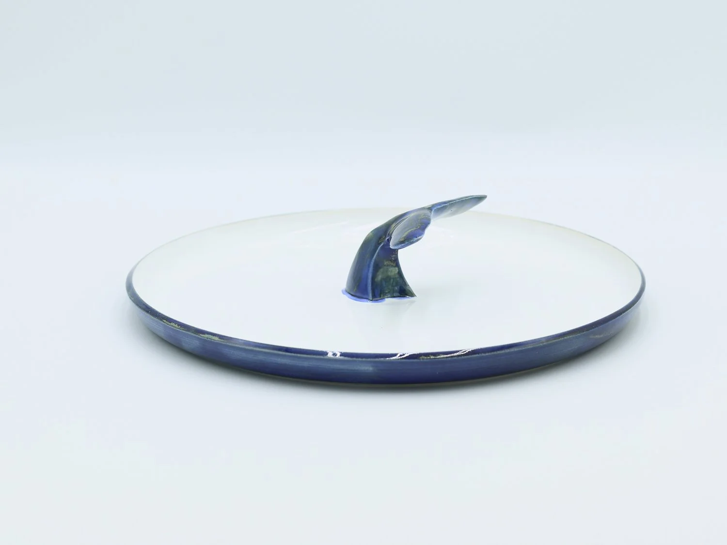 Prato em cerâmica, com cauda escura no centro, feito à mão na cor azul mar e branco no interior
