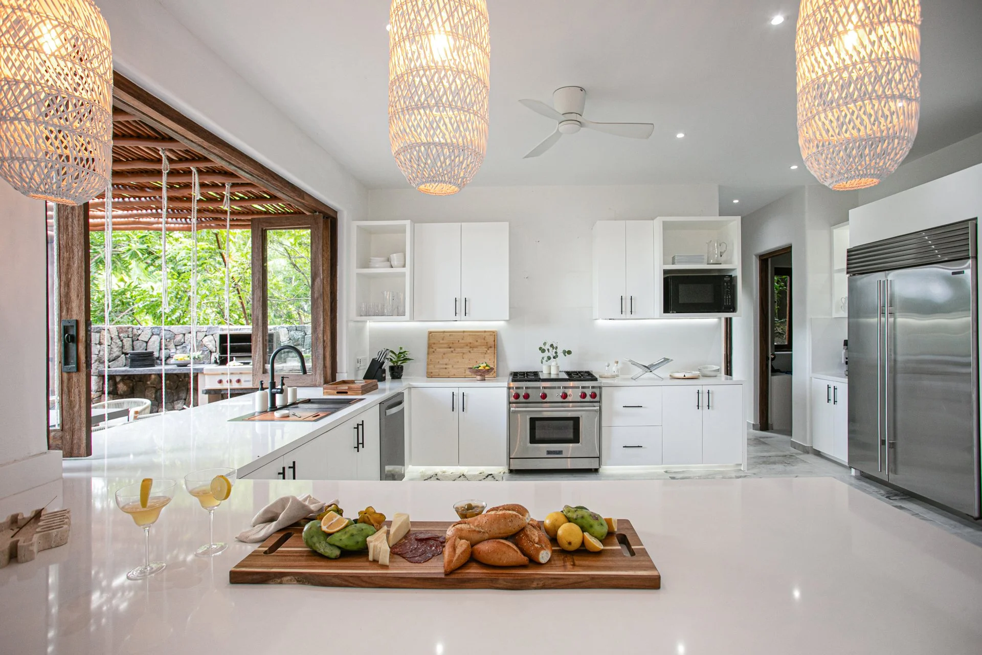 A full gut kitchen renovation featuring white custom cabinetry, Wolf and GE Cafe appliances, bespoke lighting and a farmhouse sink.