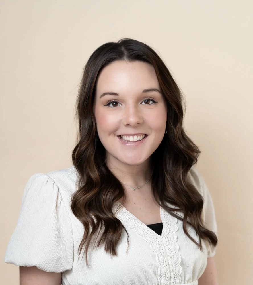 young female with brown hair wearing a white shirt