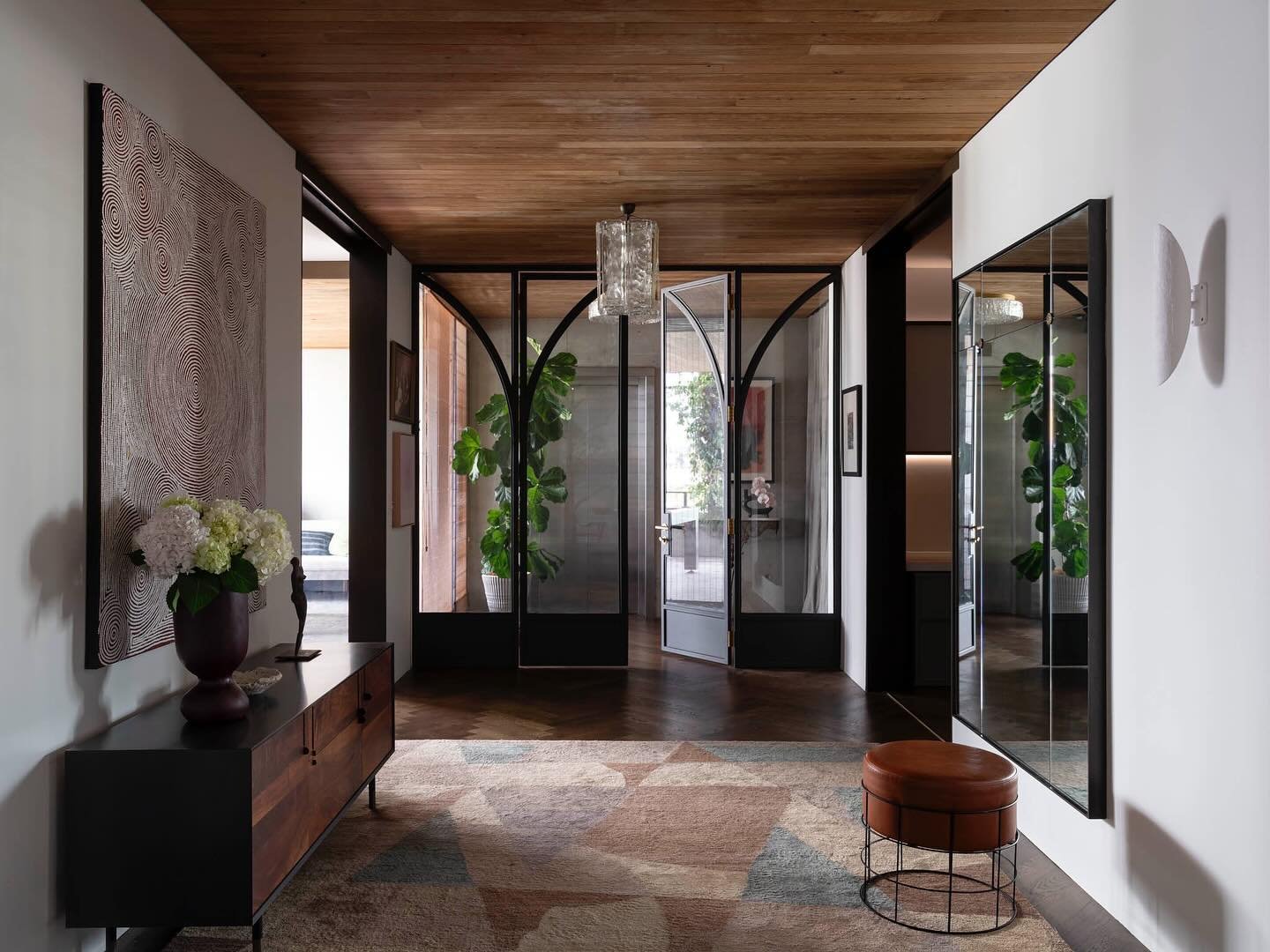 NEWSTEAD APARTMENT. Entry Hall. Once a blank canvas, our entry hall has been thoughtfully curated to convey warmth and character. The addition of metal-framed doors, timber ceiling, suede curtains and bamboo blinds has created a space that feels both
