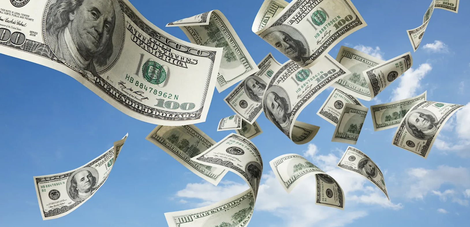 Dozens of hundred-dollar bills flutter through a blue sky against scattered clouds.