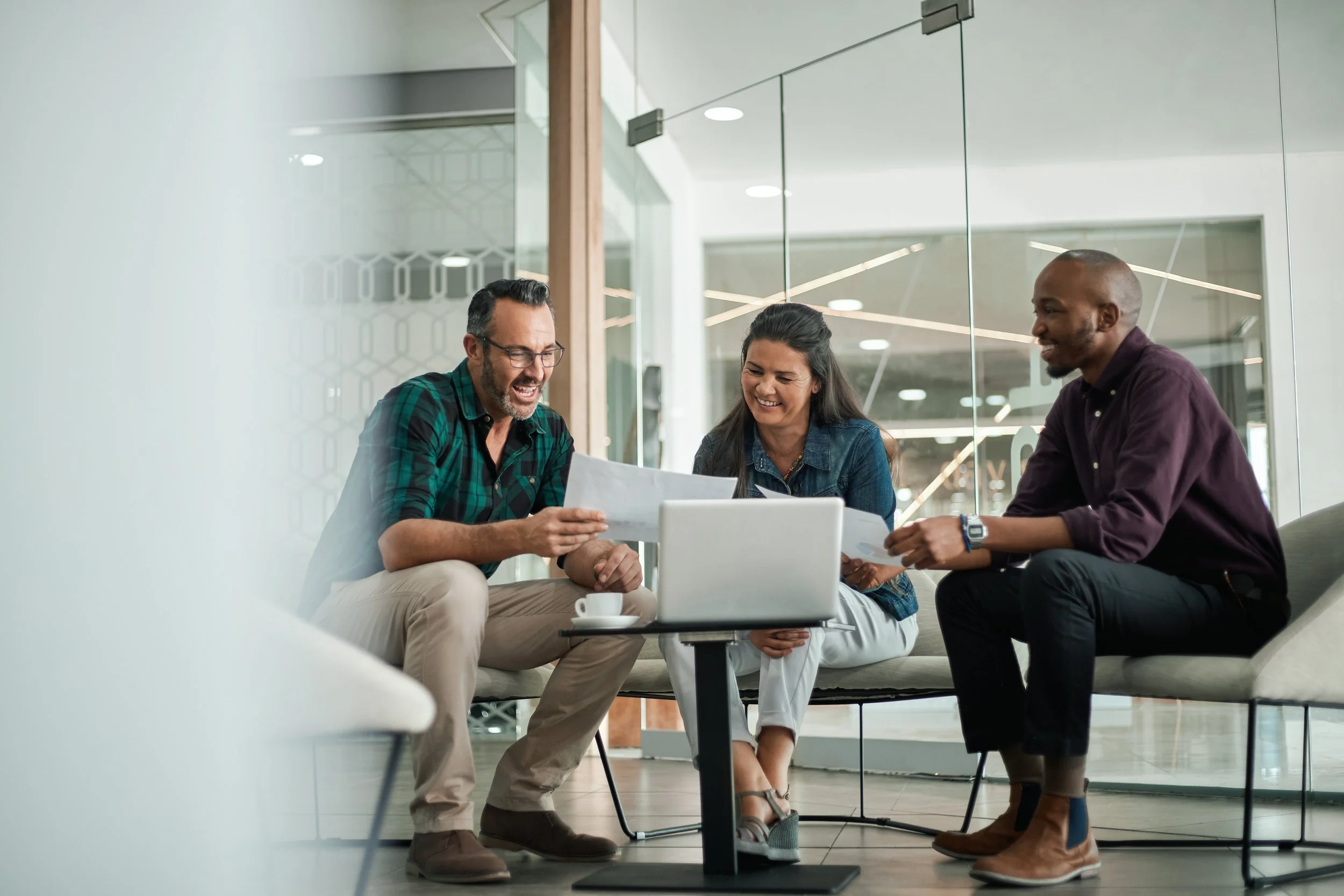 Three people looking over papers and a computer in a meeting