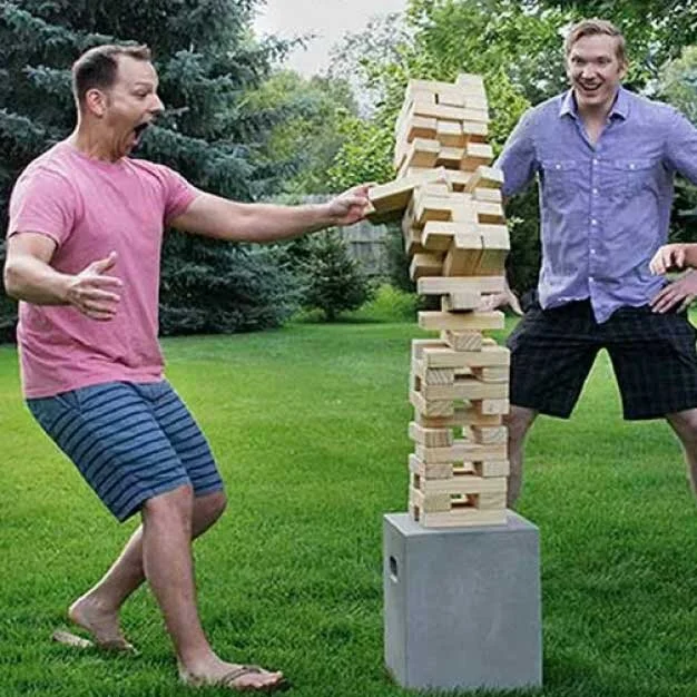 Two men playing giant Jenga on a lawn