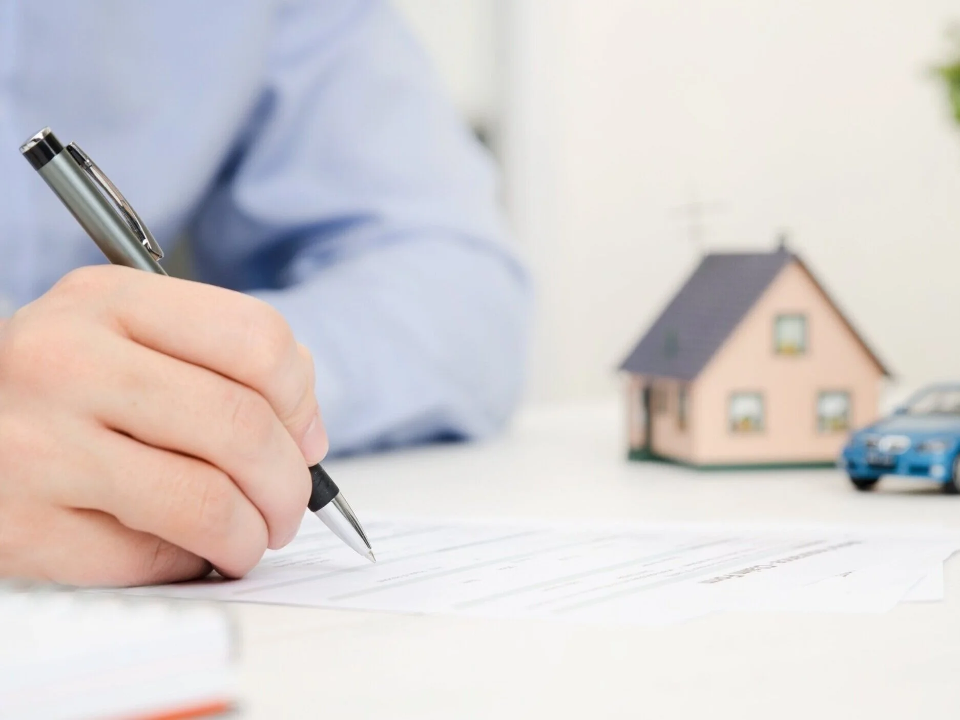 insurance agent writing homeowners policy for client at desk