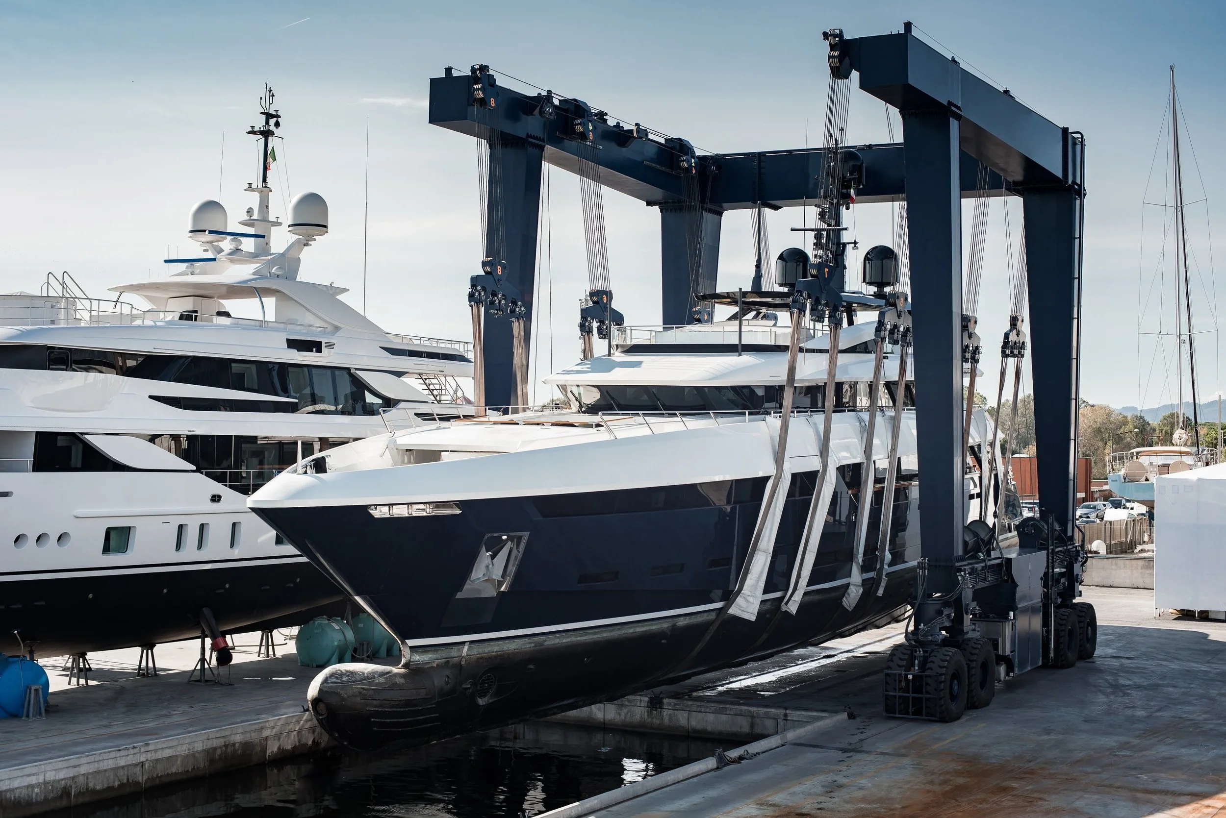 Super Yacht hauled out in shipyard, being lifted by industrial crane for refit or maintenance yard period
