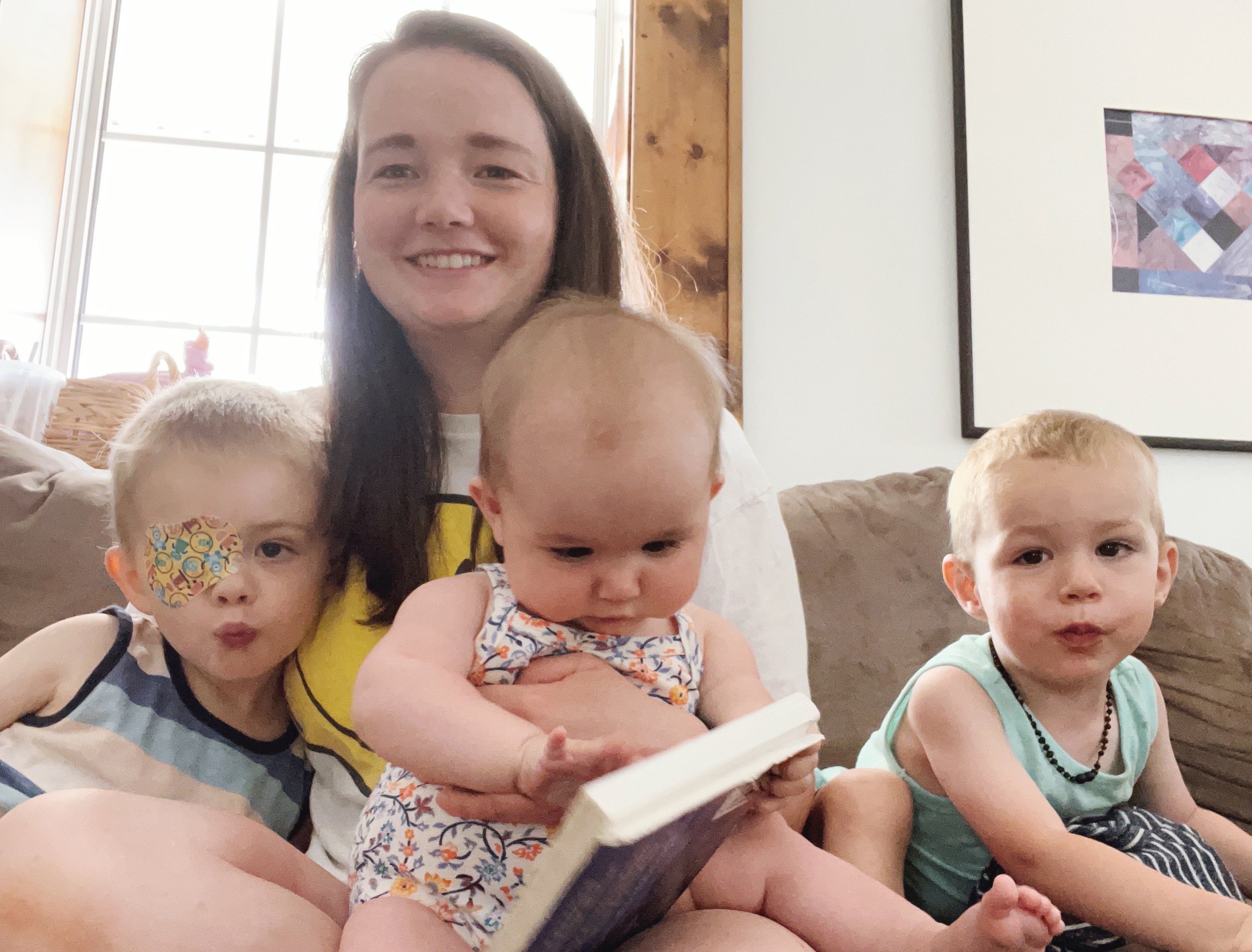 Sarah Adema Blog Healthy Habits for a Busy Mom. Sarah with three of her kids reading books on the couch.