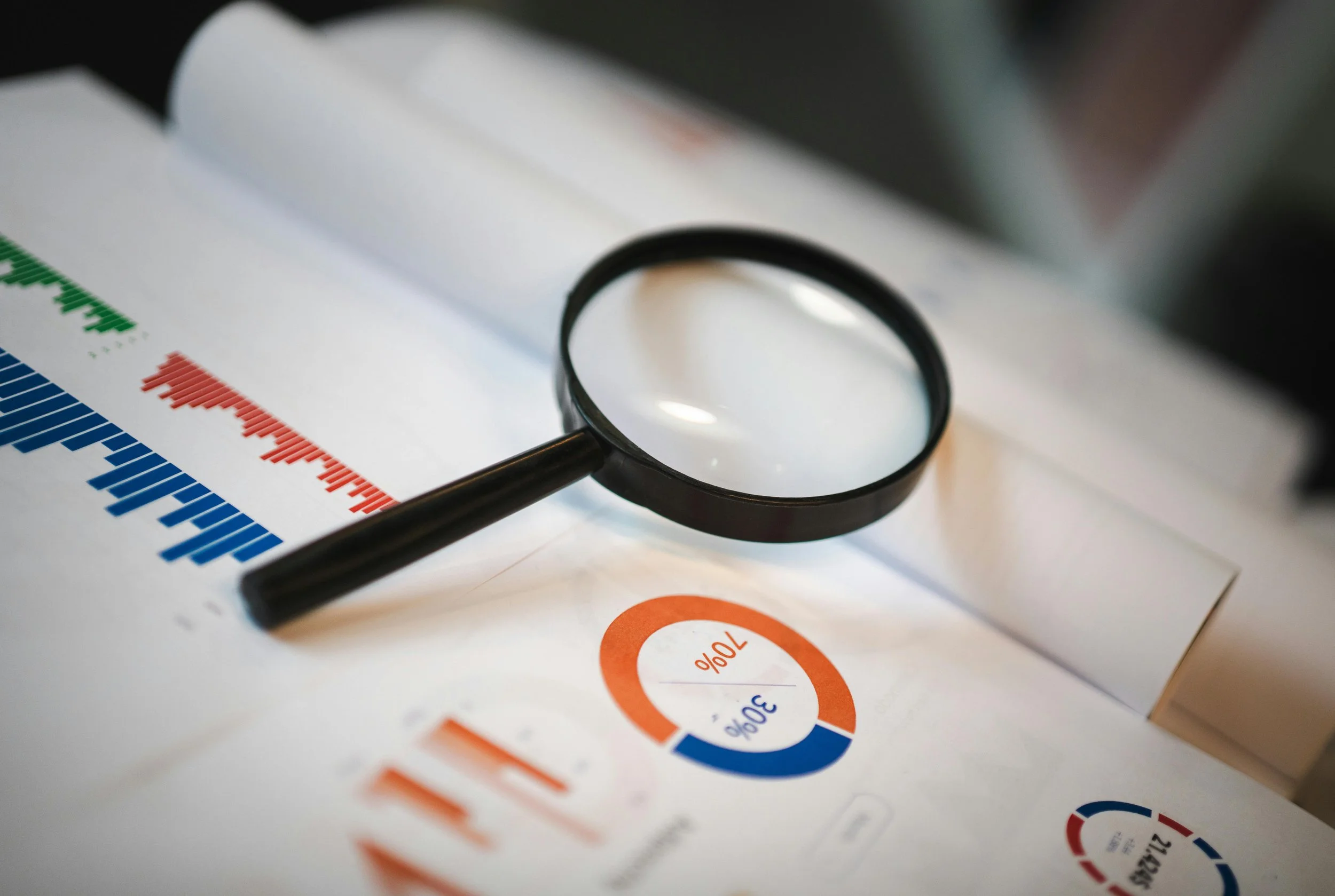 A magnifying glass placed on financial graphs and charts