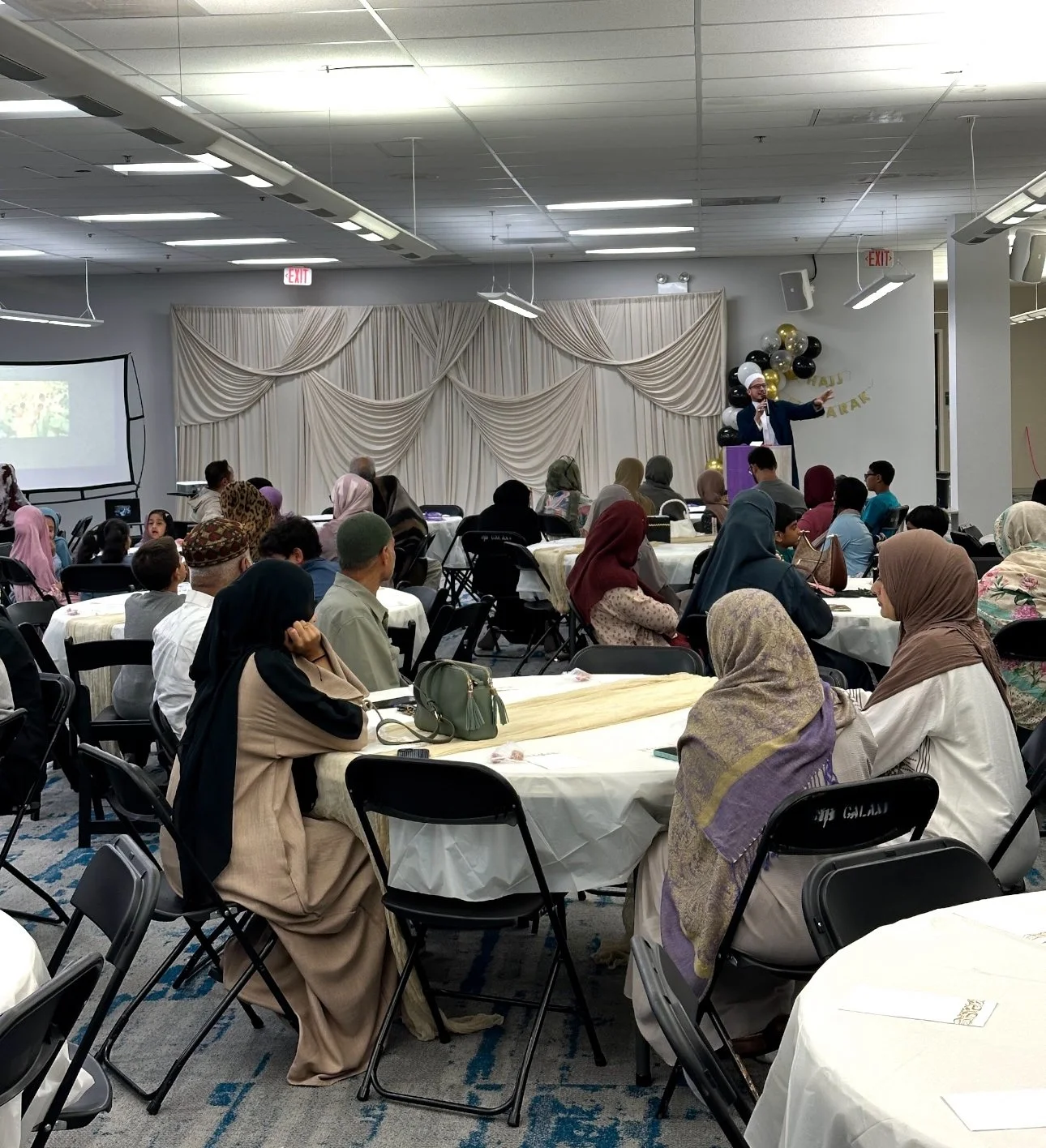 Guests at round tables listening to a speaker in the MFC hall