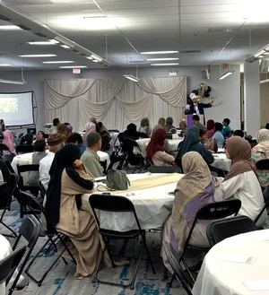 Guests at round tables listening to a speaker in the MFC hall