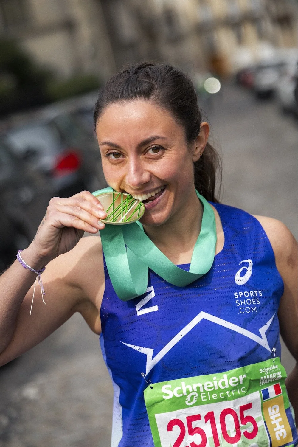 Finisheuse qui croque sa médaille après un marathon, portrait de coureuse pour ASICS