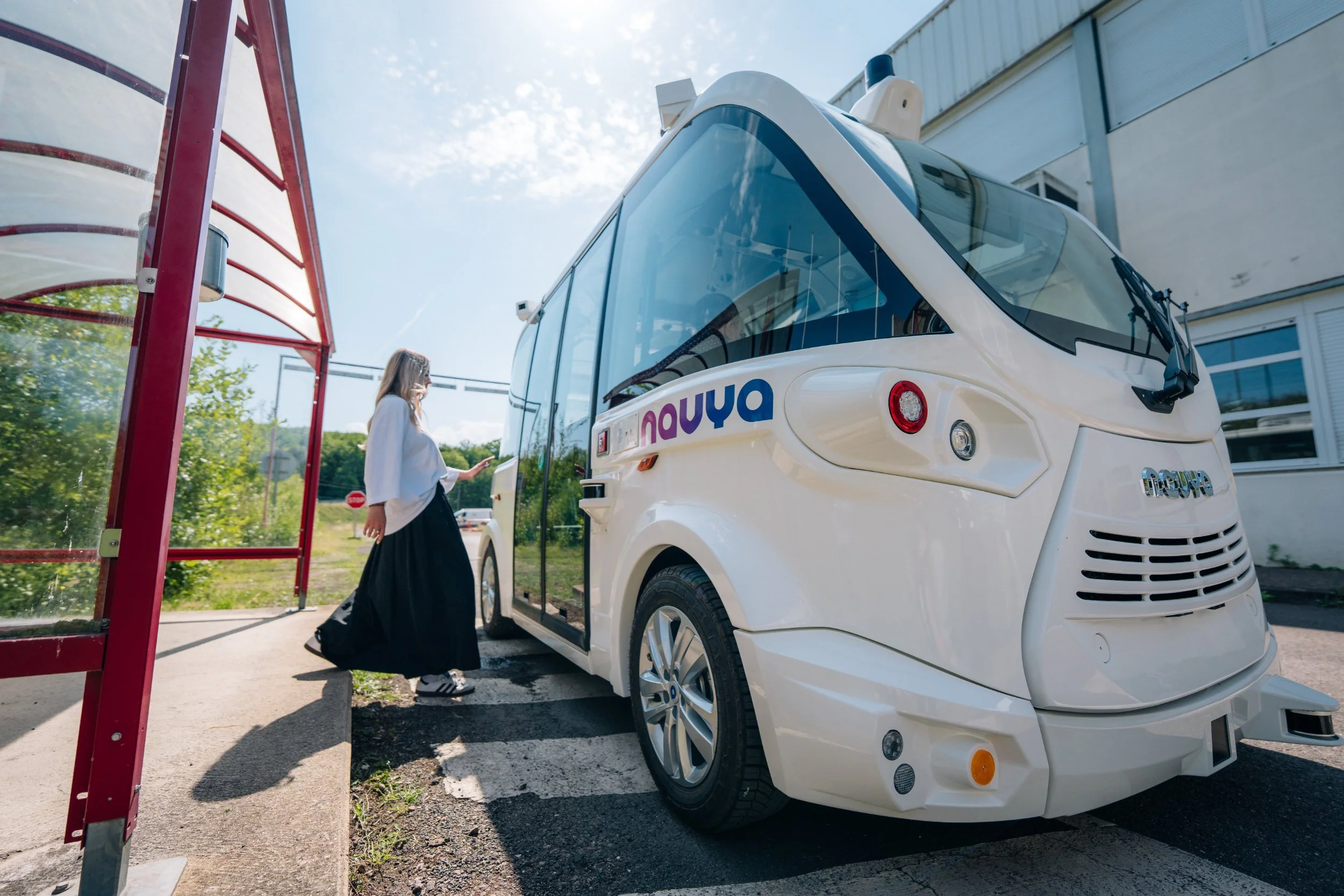 Voyageuse à un arrêt devant la navette autonome Navya Mobility
