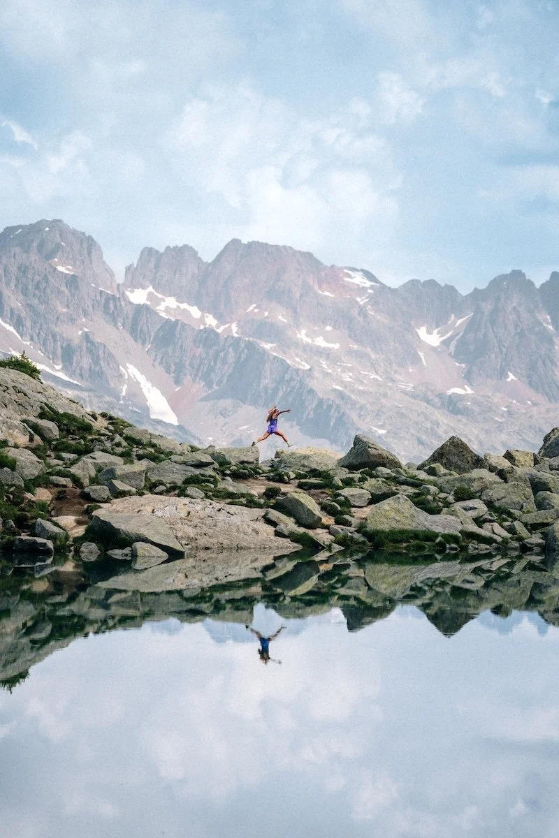 Traileuse New Balance au bord d'un lac d'altitude face aux aiguilles de Chamonix, photographie trail dans les Alpes