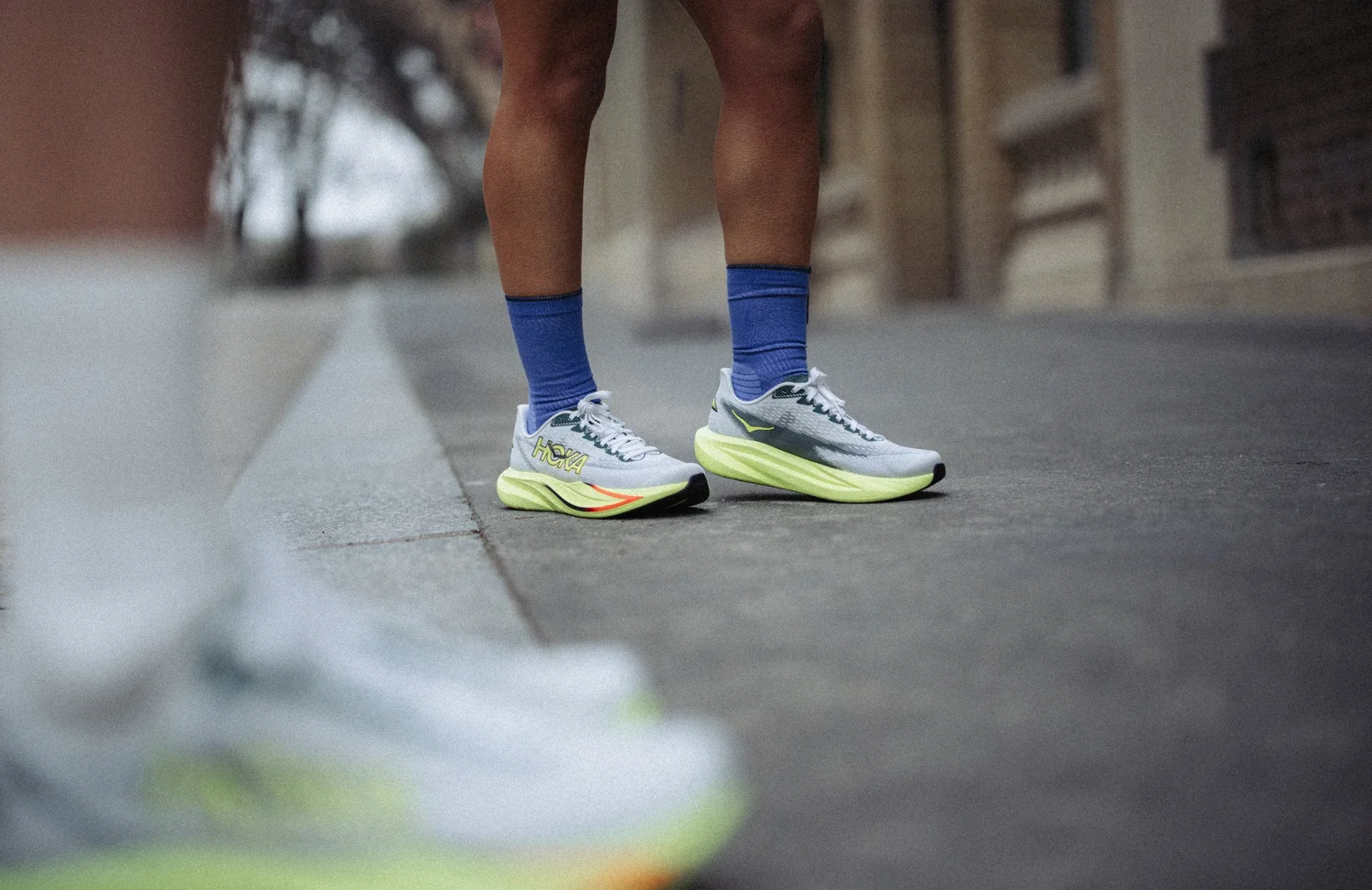 Chaussures de running HOKA au bord d'un trottoir, photographie produit en situation
