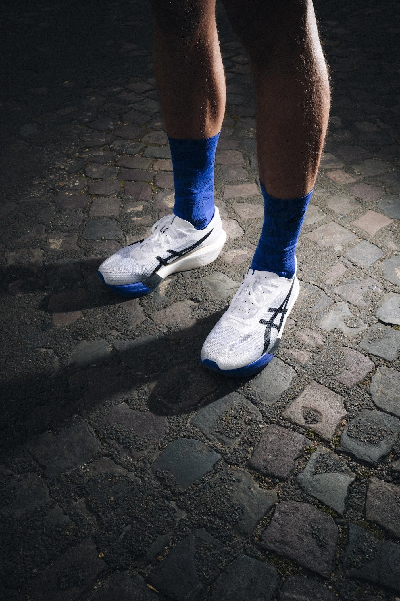Chaussures ASICS d'un coureur sur des pavés, couverture photo et vidéo d'un marathon