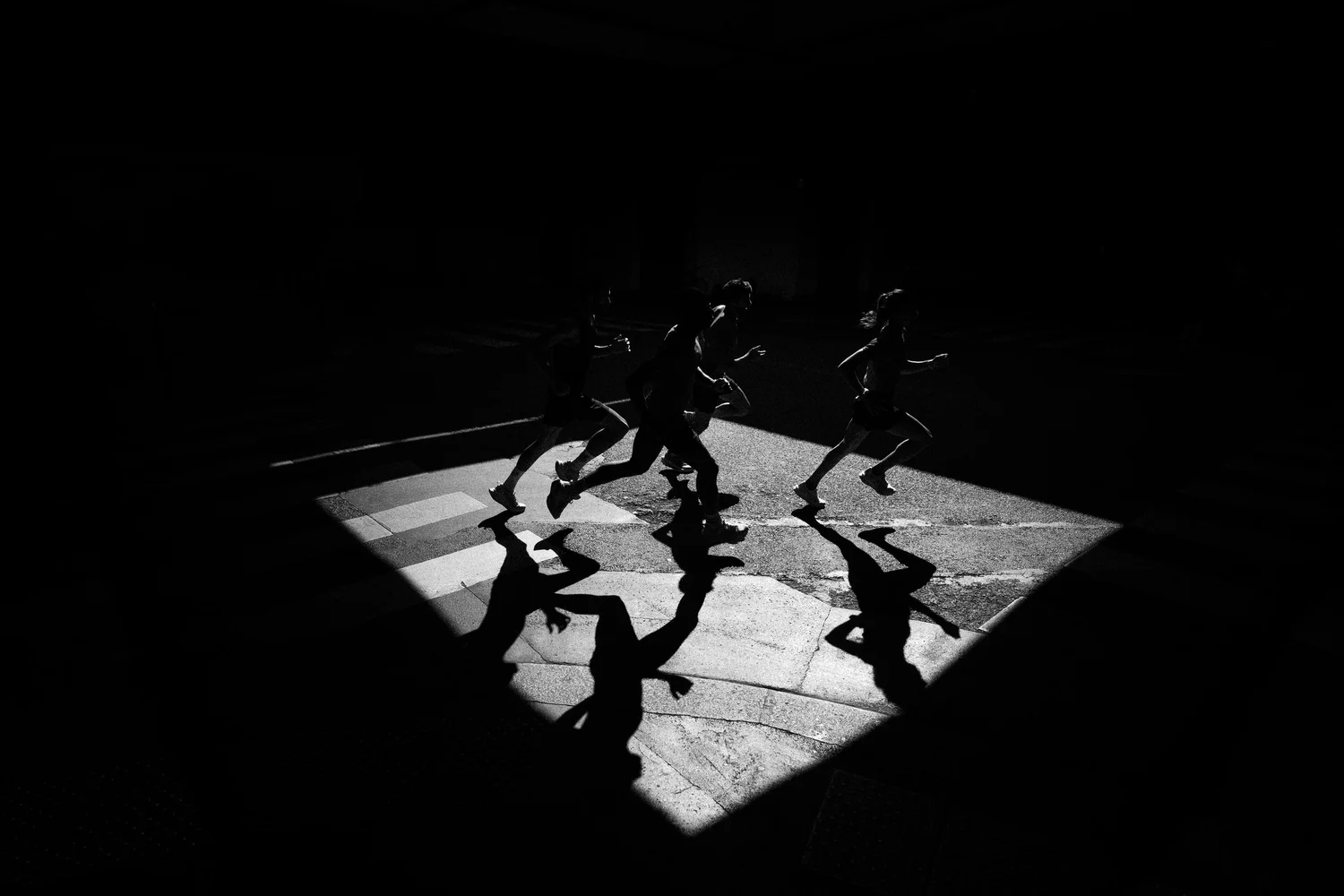 Ombres de coureurs projetées sur des pavés, photographie running en noir et blanc