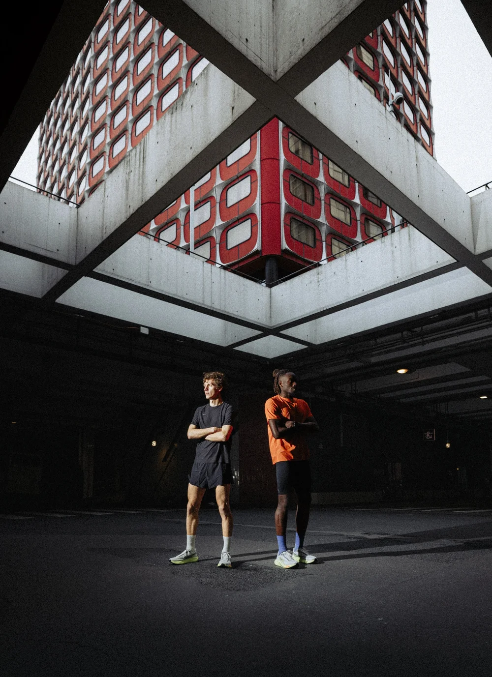 Deux coureurs HOKA sous une architecture de béton, campagne photo de lancement de chaussure