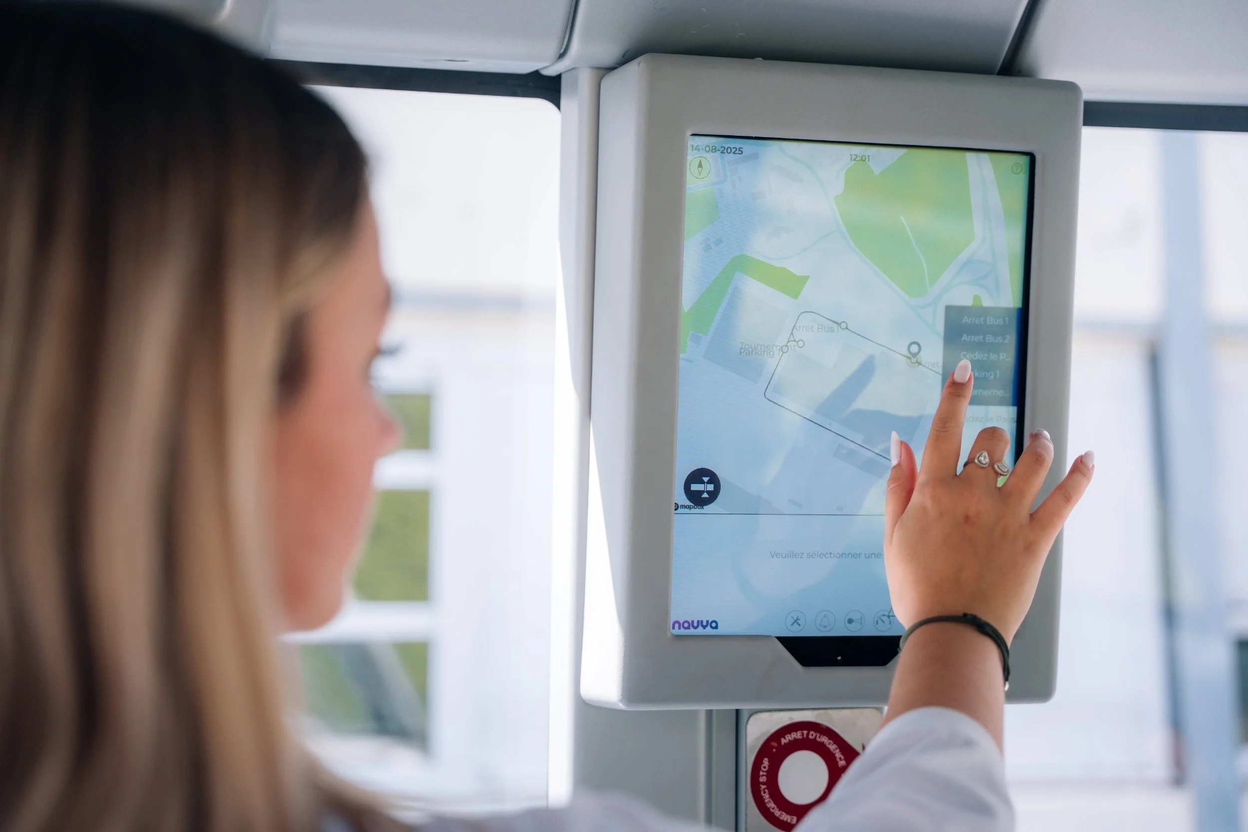 Main sur l'écran tactile passager de la navette autonome Navya