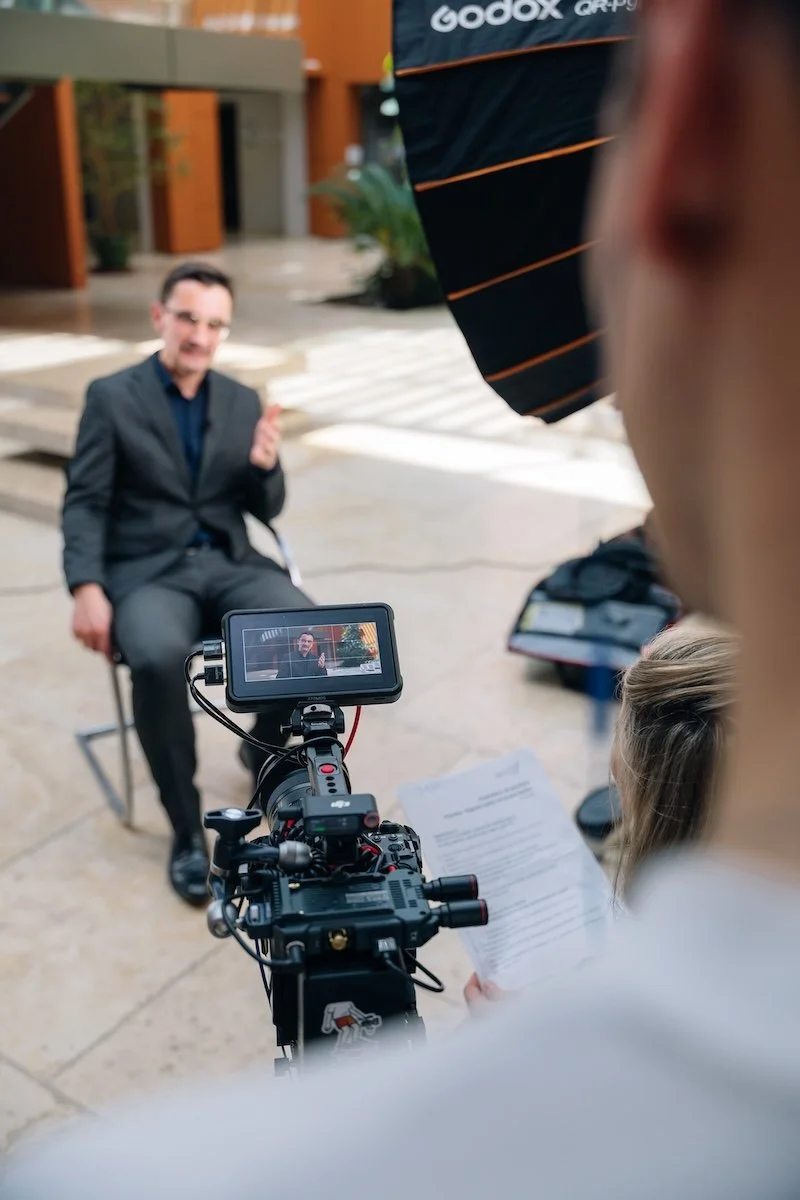 Interview filmée d'un dirigeant en costume, caméra et moniteur au premier plan, tournage corporate à Paris