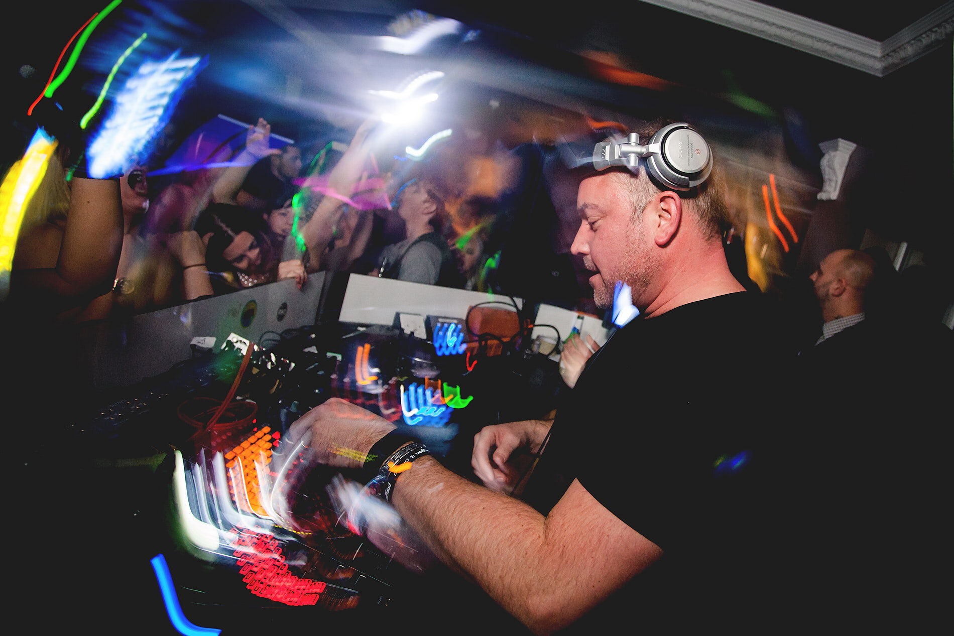 DJ performing at decks with swirling lights
