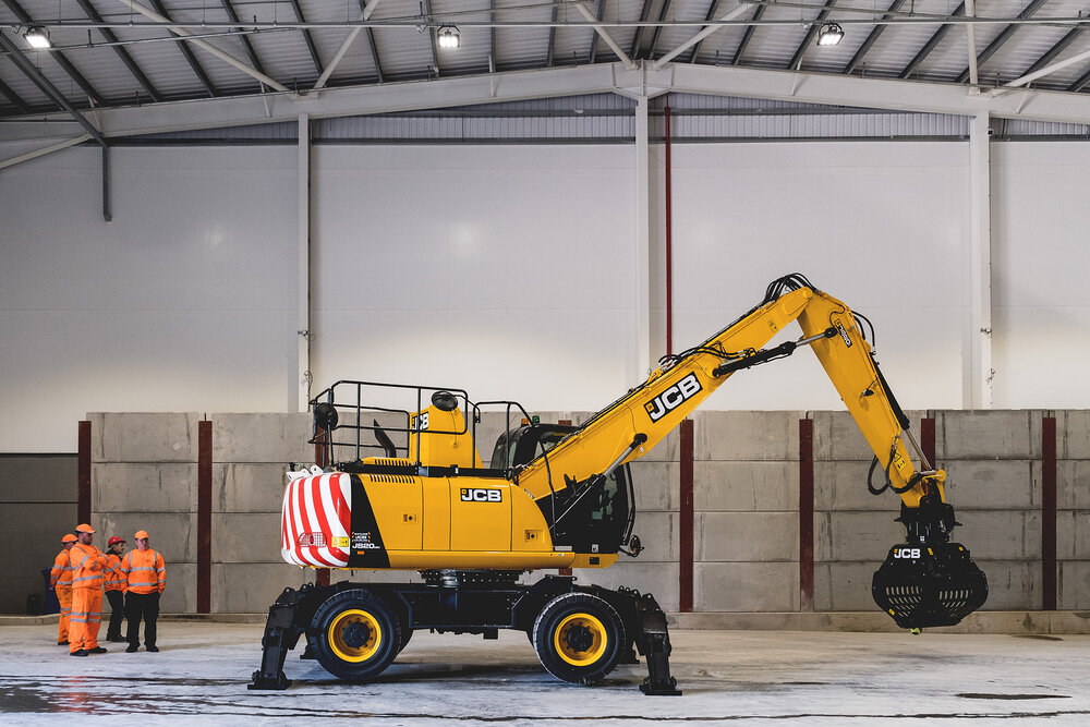 image of JCB in large hanger with group of workmen