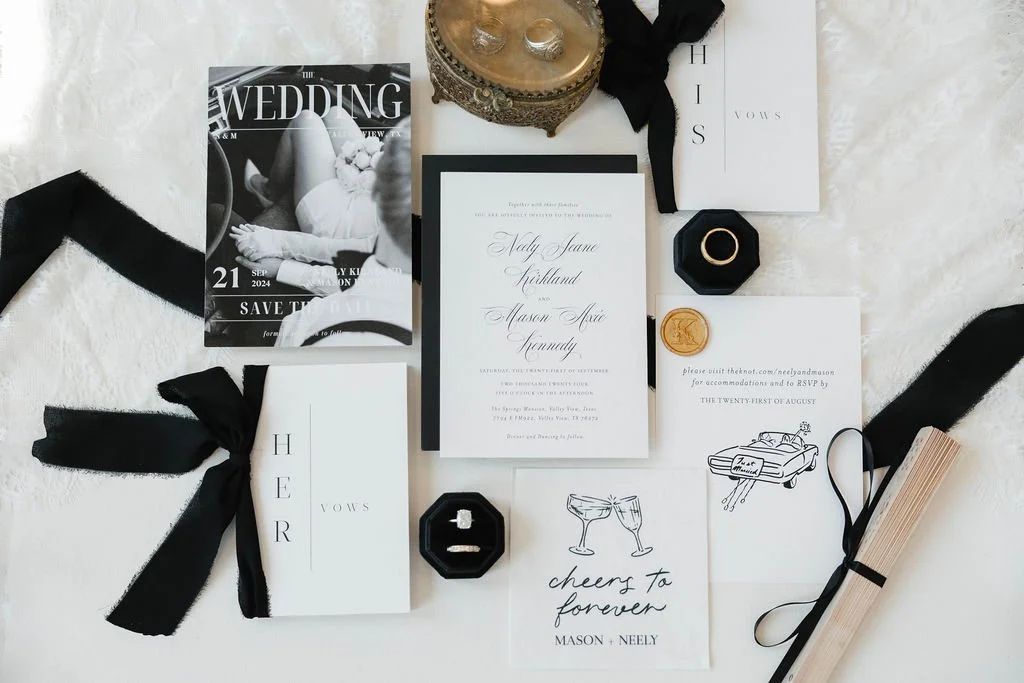 Wedding stationery ensemble featuring invitations, save-the-date card, vow booklets, ring box, and decorative elements like ribbons and wax seal.