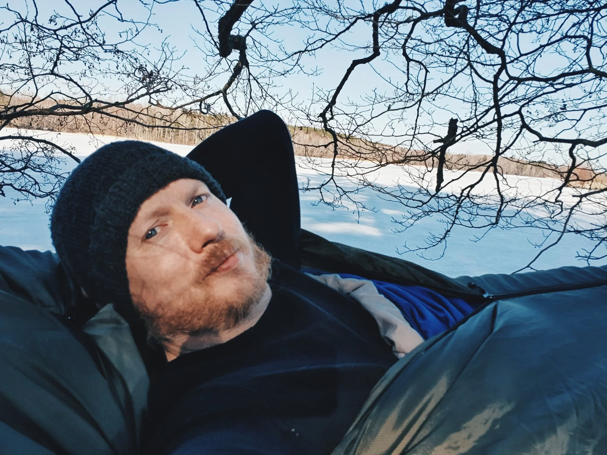 Kristoffer-Robin ligger i en hängmatta med snö i bakgrunden.