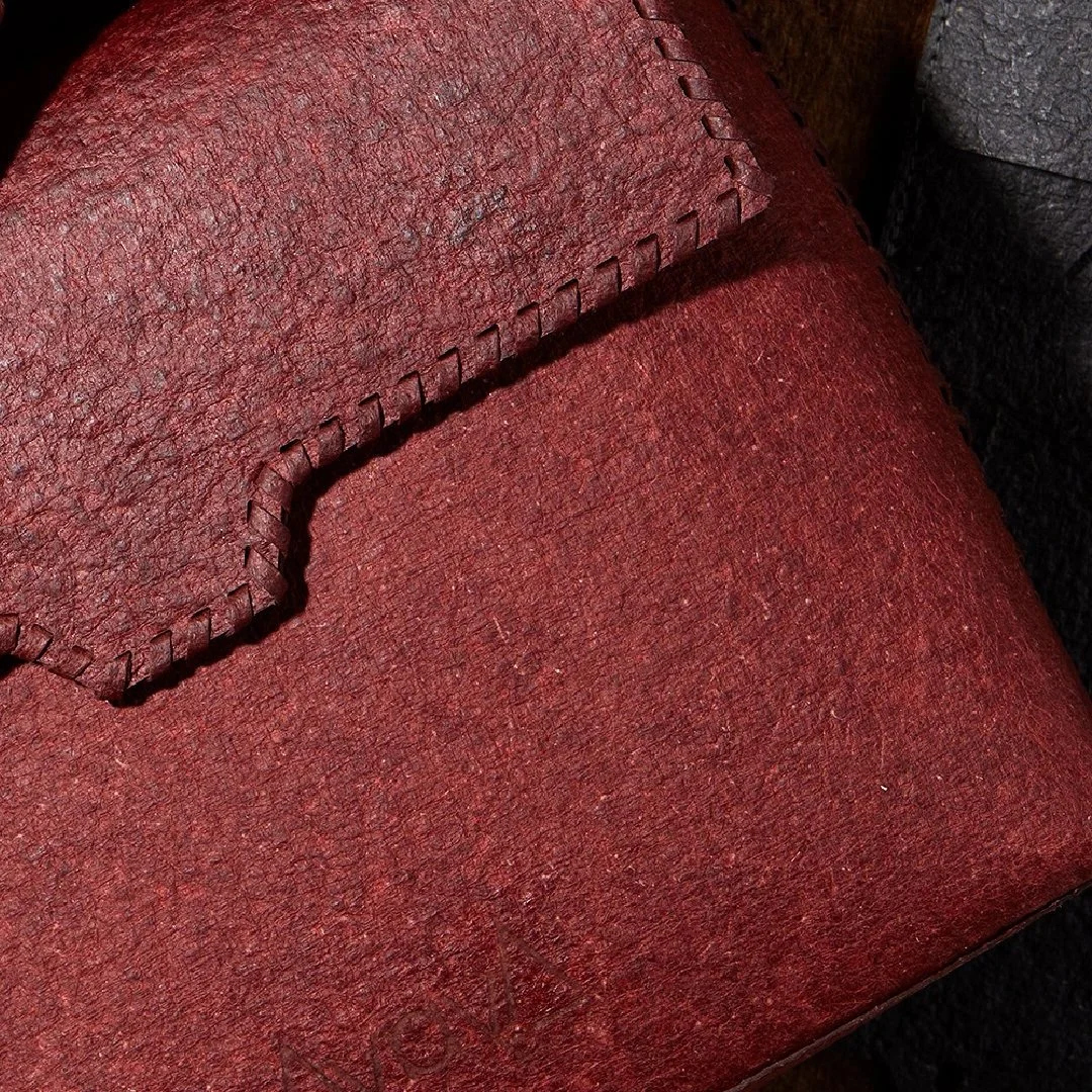 Close-up of a red handbag showing a stitched edge and textured leather.