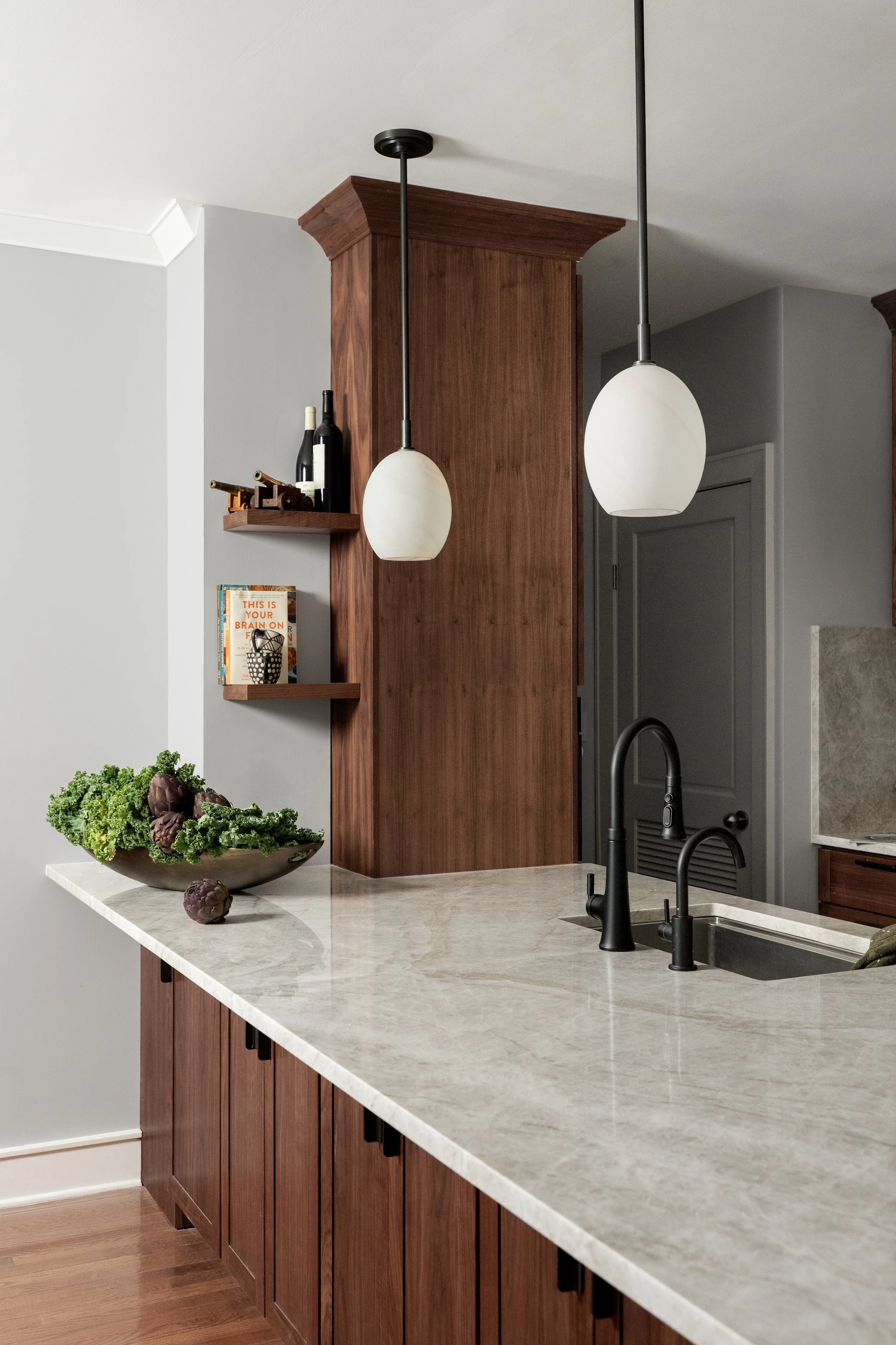 Modern minimalist kitchen featuring walnut cabinetry and waterfall island.