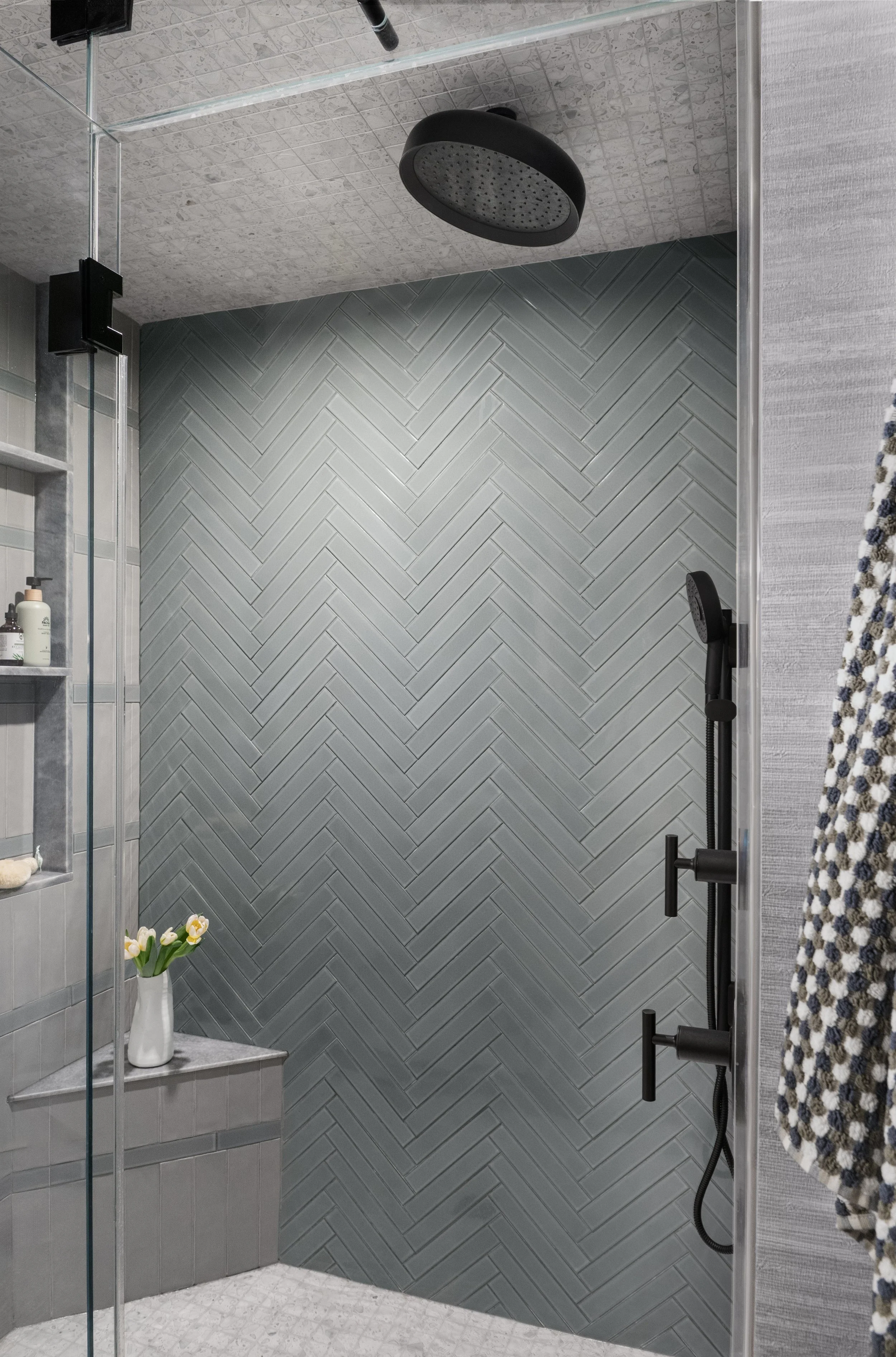 Zen-inspired bathroom with vertical herringbone tile and black fixtures.