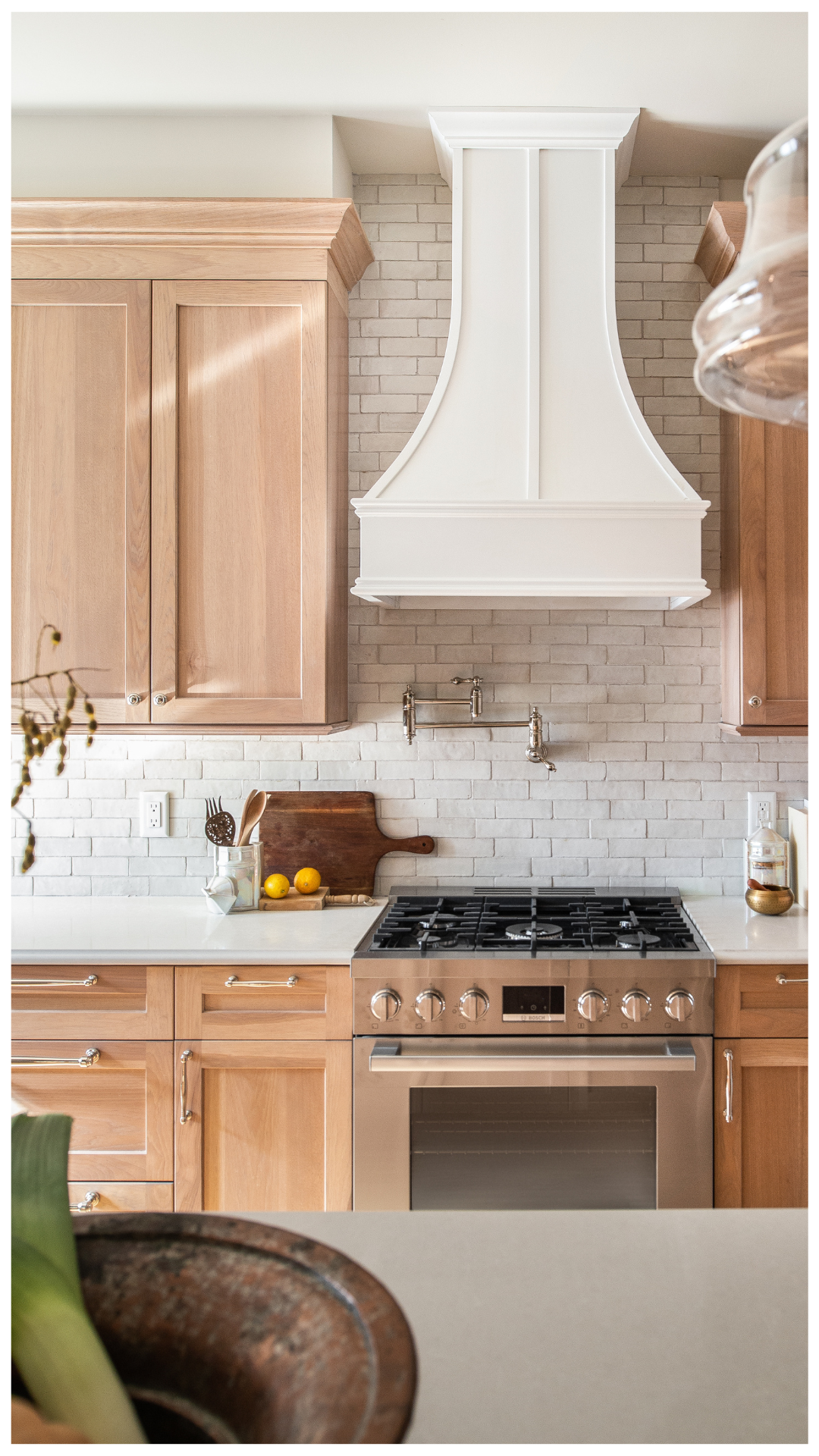 An elevated culinary environment featuring an arched architectural threshold, custom white oak cabinetry, and a refined kitchen island with leather woven stools, designed for seamless hosting and a high-performance lifestyle