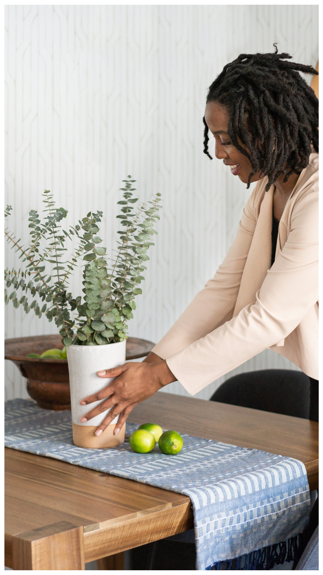 A cohesive open-concept living and dining orchestration featuring a blue sectional, mid-century modern wood dining table, and geometric wallpaper, designed for clear spatial definition and functional flow.