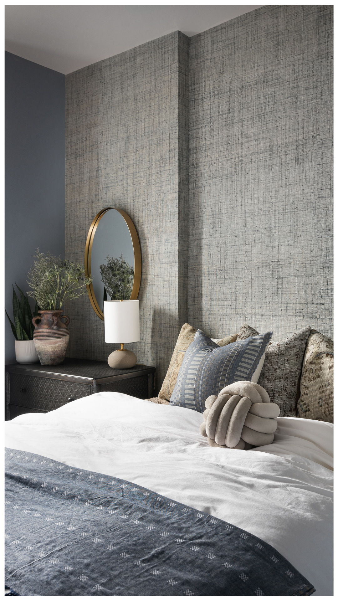 A 5-star residential retreat featuring a curved architectural partition in dusty blue, textured designer wallcovering, and a modern brass chandelier, engineered to integrate a luxury walk-in closet within the existing footprint.