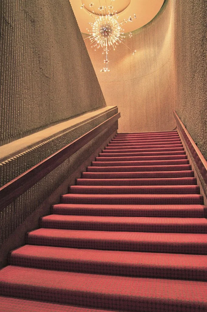 Elegant staircase with red carpet and ornate chandelier
