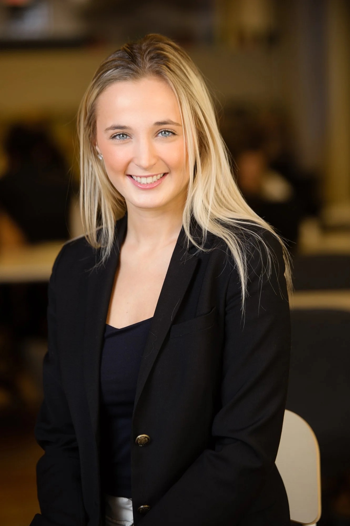 Smiling woman in business attire with blonde hair in an office setting.