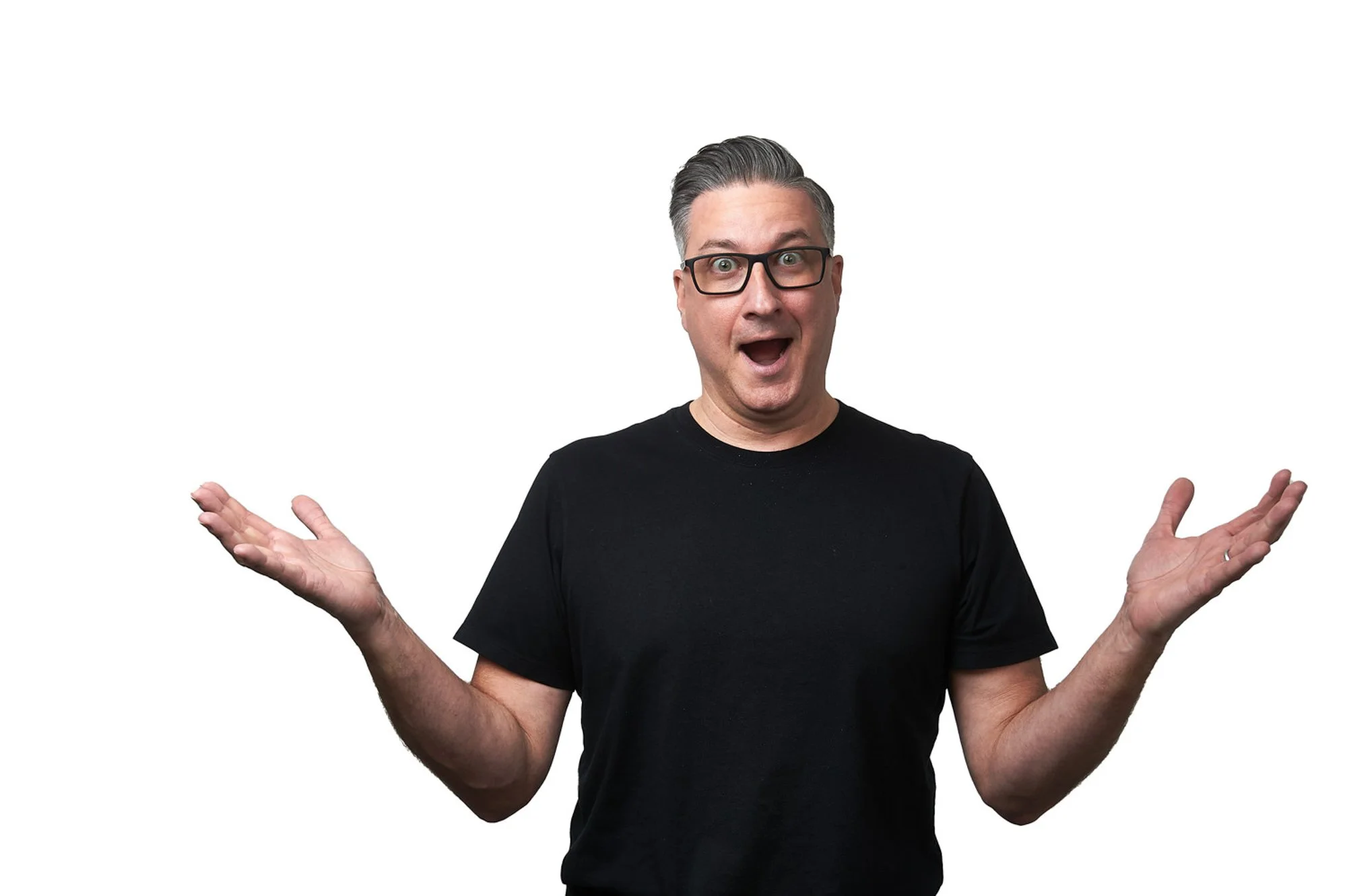 Man in black t-shirt making a surprised expression with open arms against a white background.