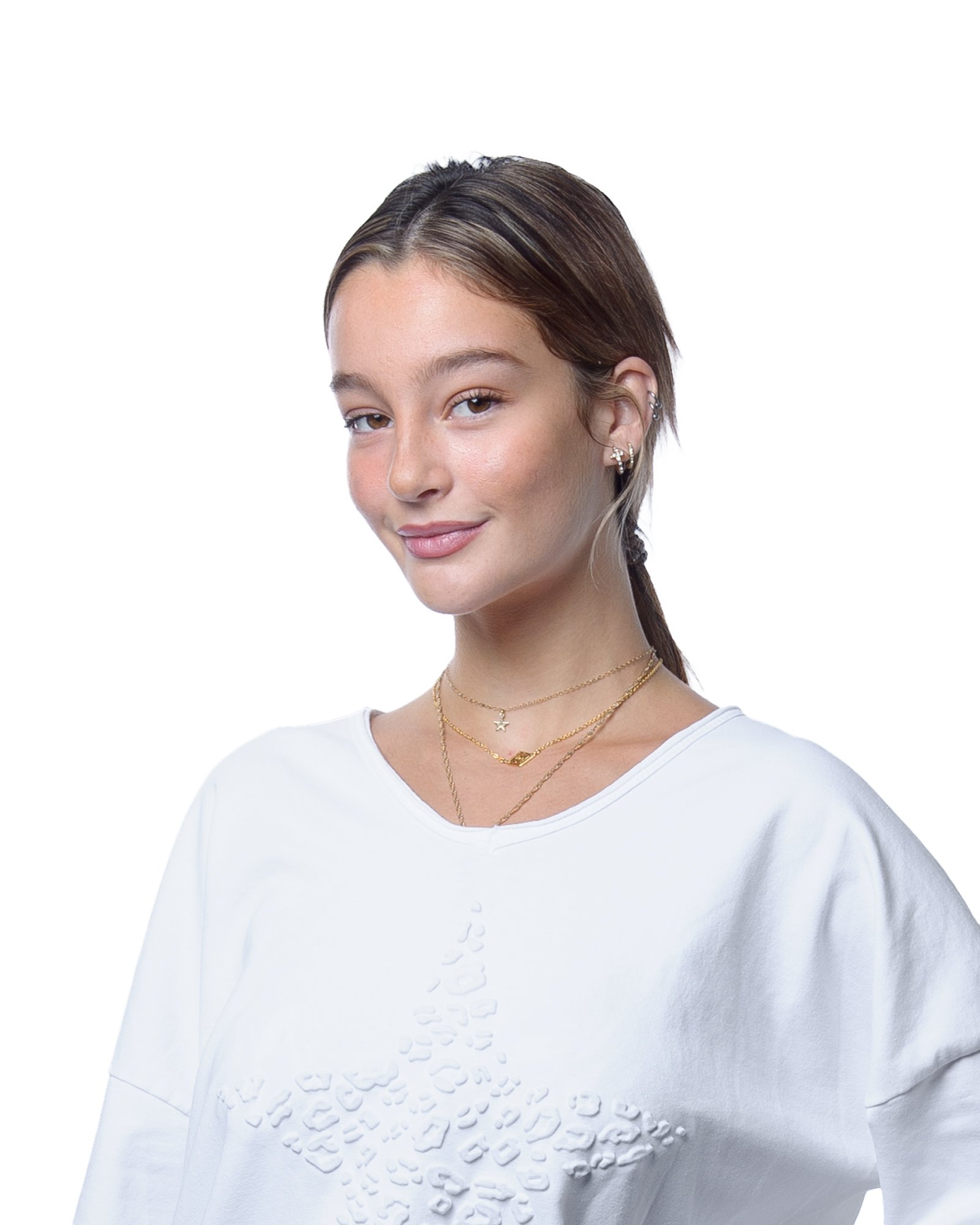 A young woman wearing a white shirt with a textured design on the front and layered gold necklaces, against a white background.
