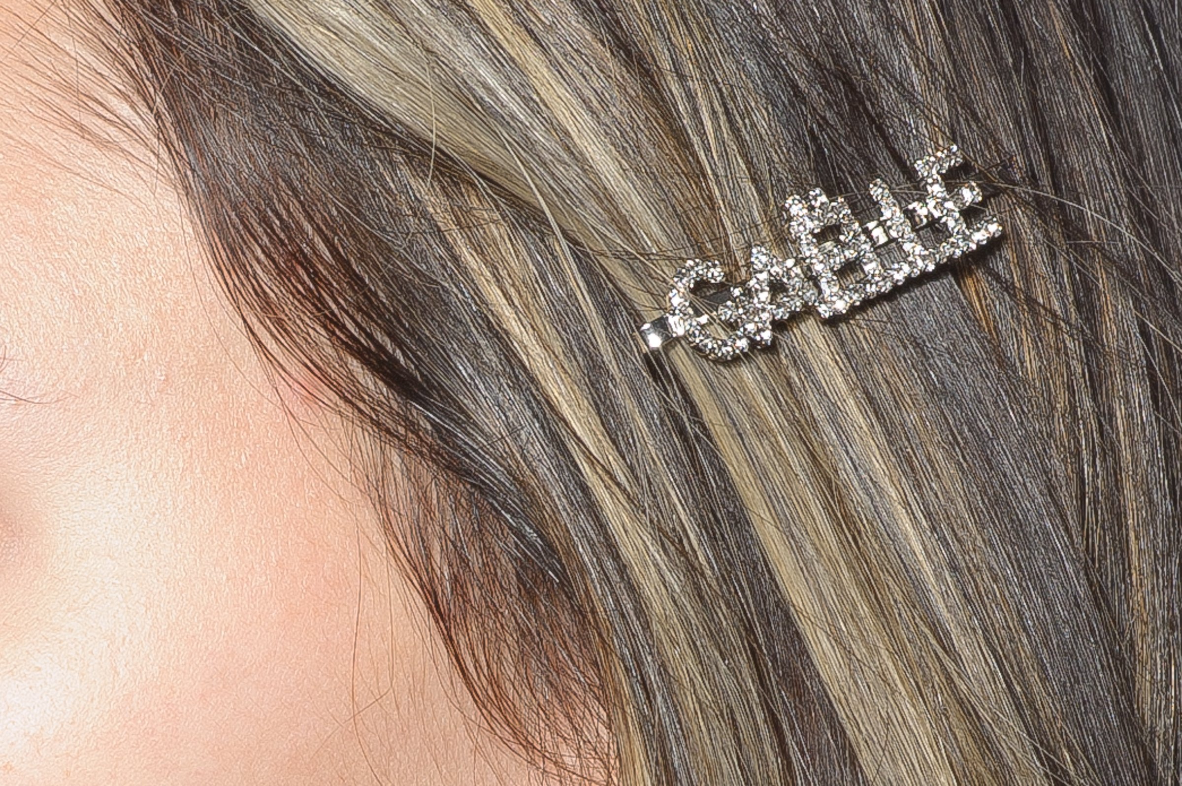 Close-up of a woman's hair with a rhinestone hair clip spelling "GABRIEL".