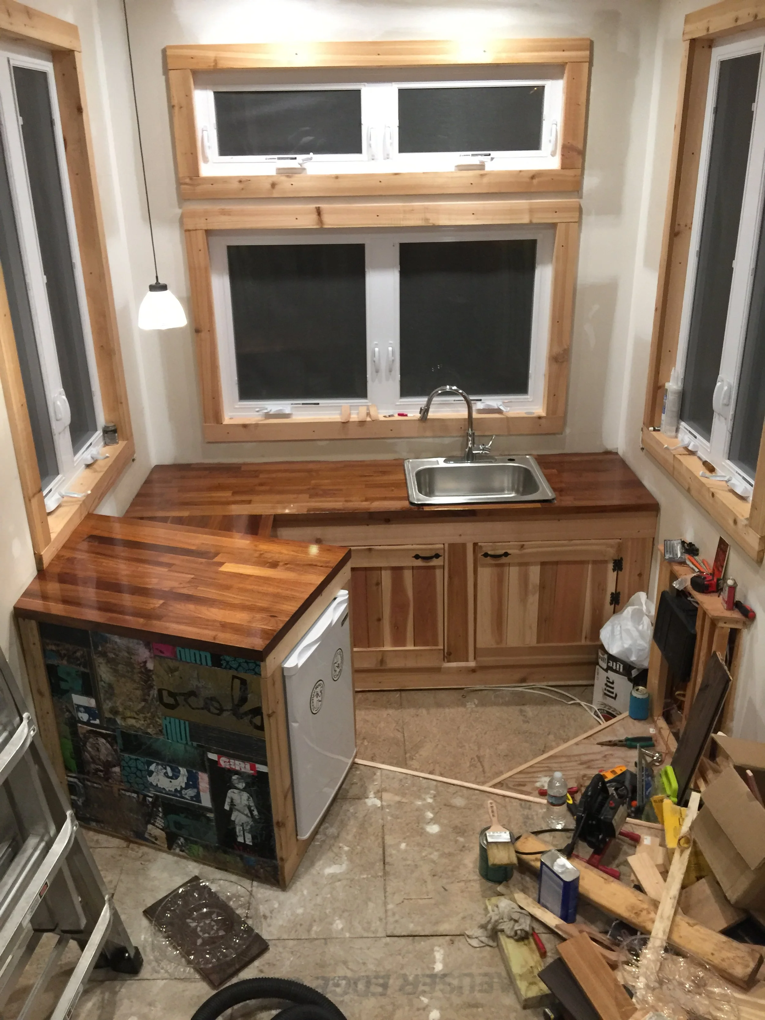 Kitchen with lots of windows, butcher block countertops, a deep farmhouse sink, and mini-fridge. 