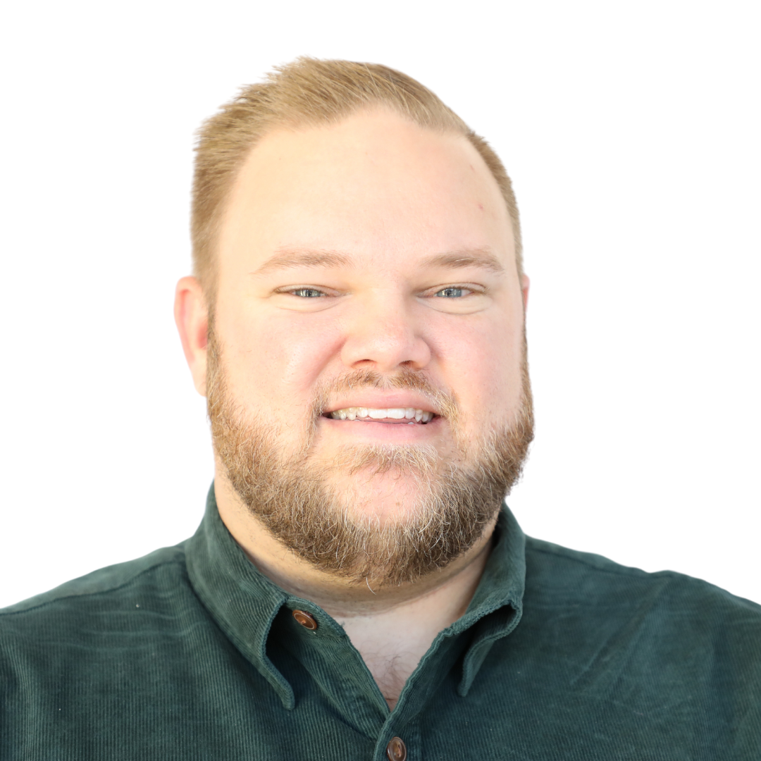 Portrait of a man with short, light brown hair and a beard, smiling, wearing a dark green collared shirt, against a white background.