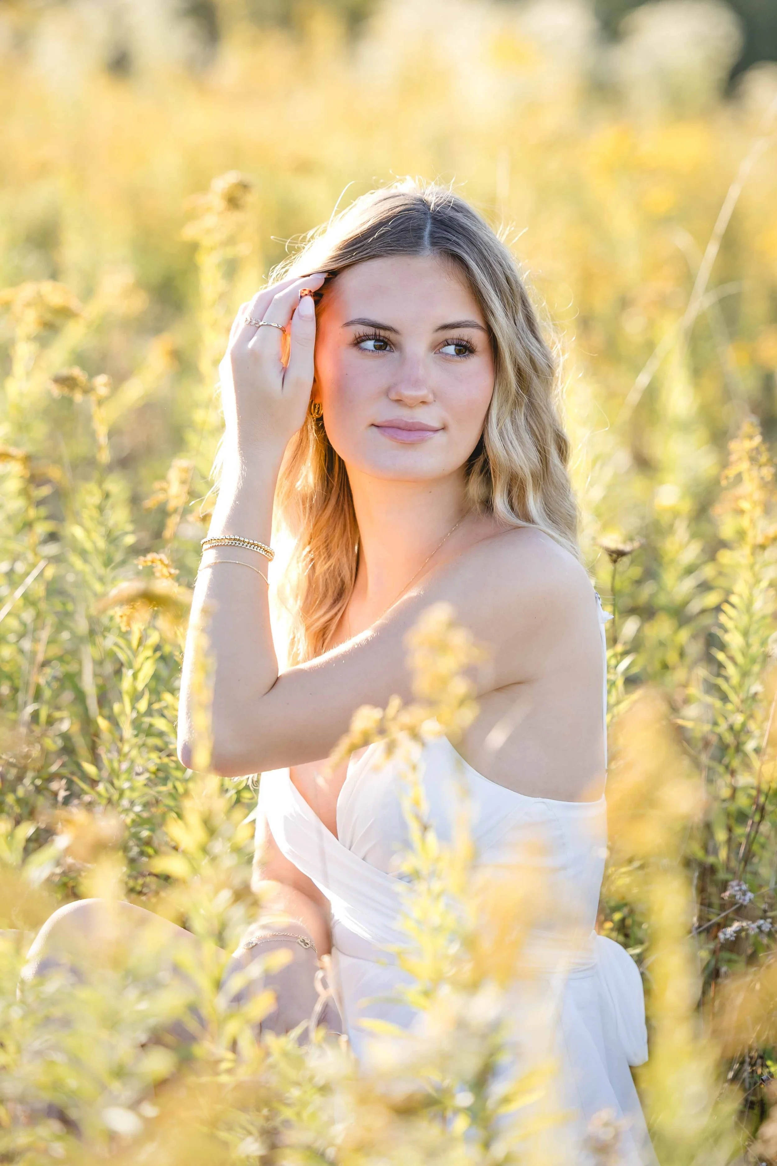 girl in field of high grasses flowers in white dress