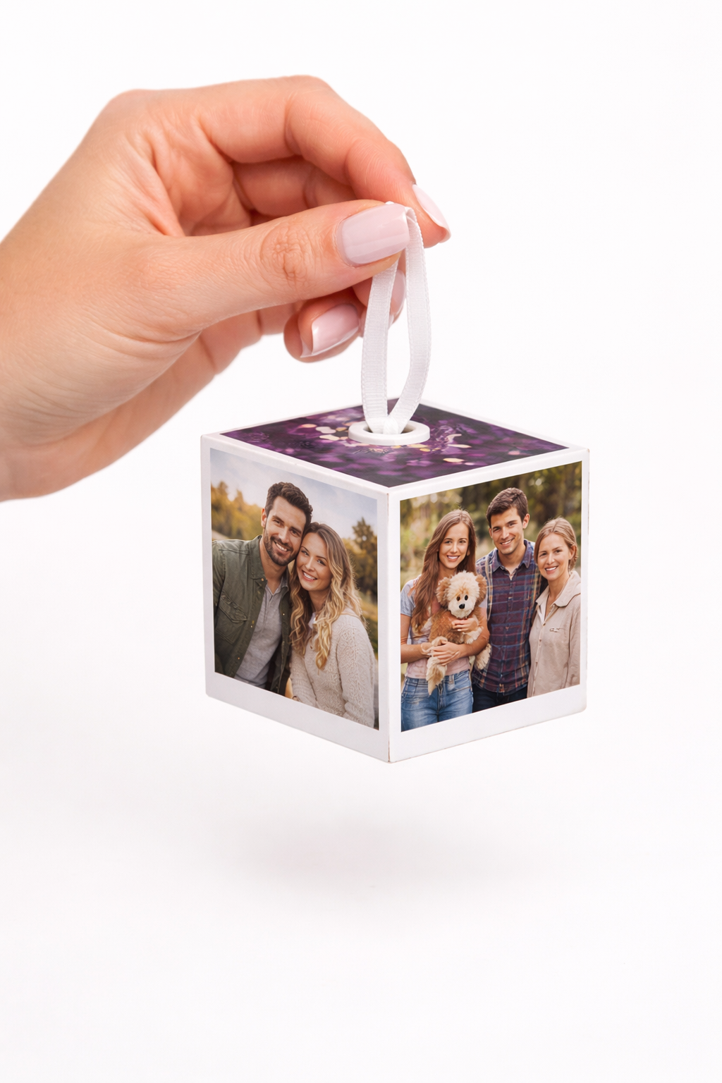 A photo cube ornament with three sides visible, each displaying different photos with white ribbon attached to the top of the cube.