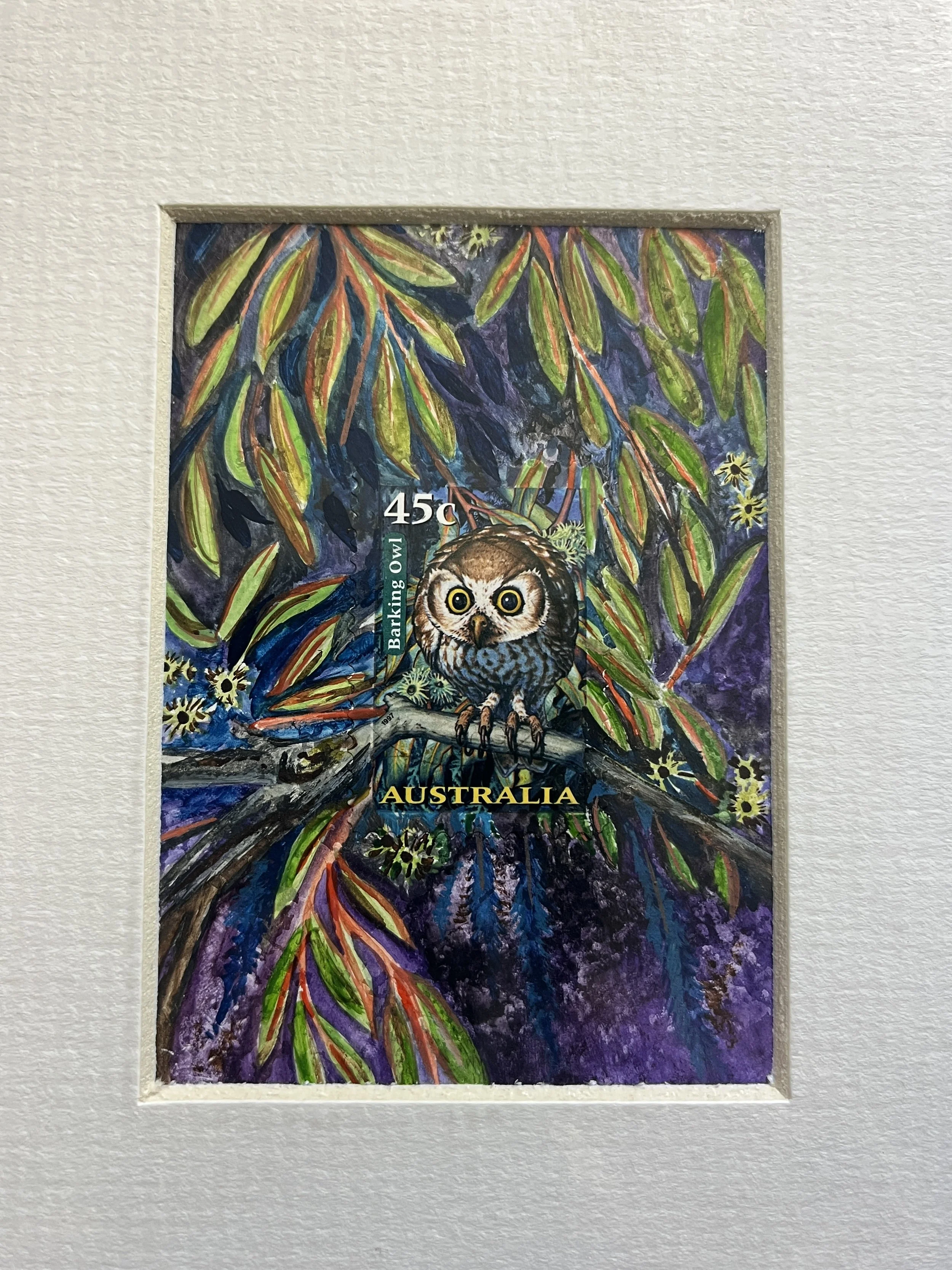 a small mounted artwork showing an owl at the center, with purple and green tones in the bushes around it.